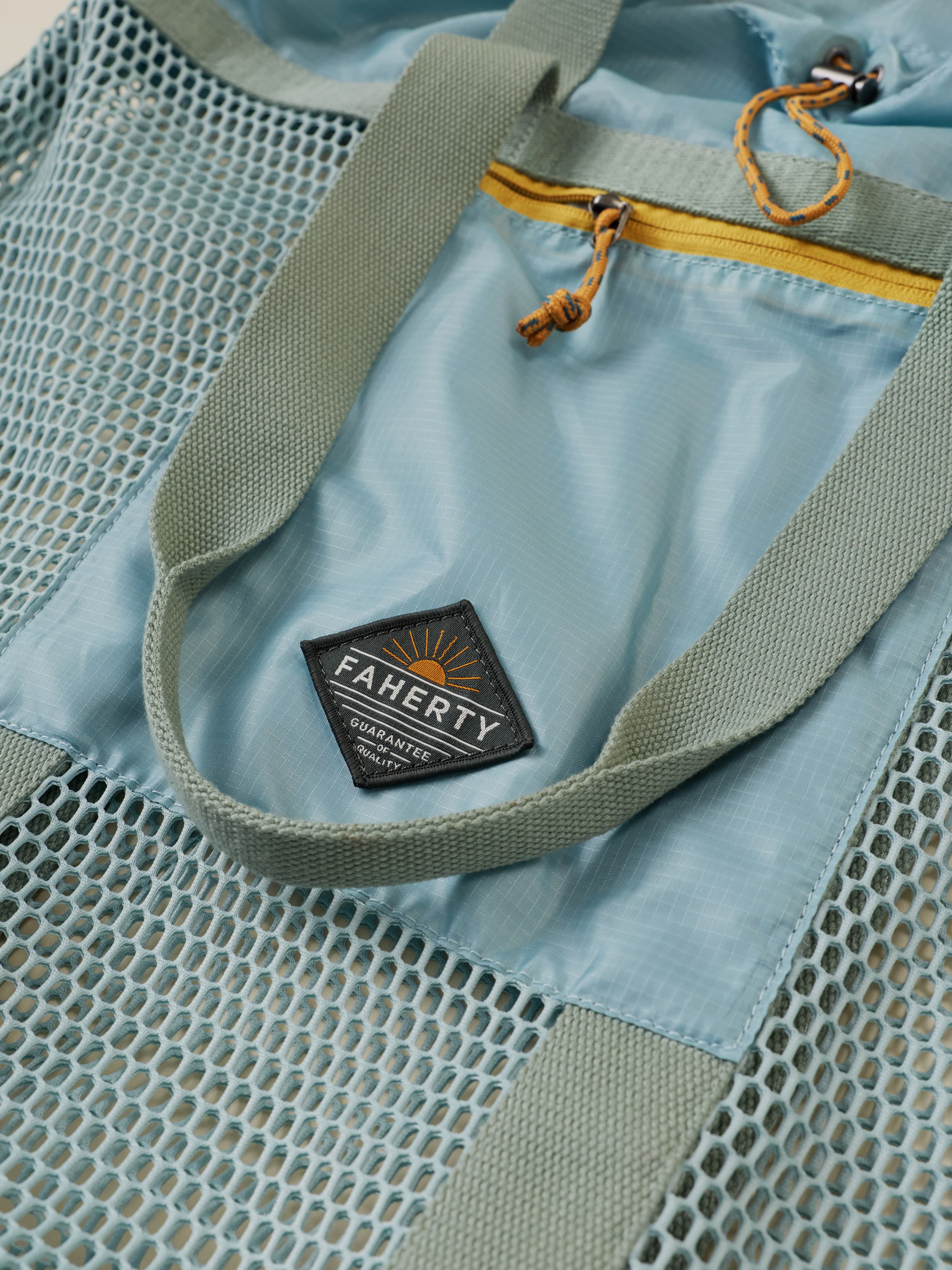 Light blue bag with mesh side and visible 'Faherty' brand logo.