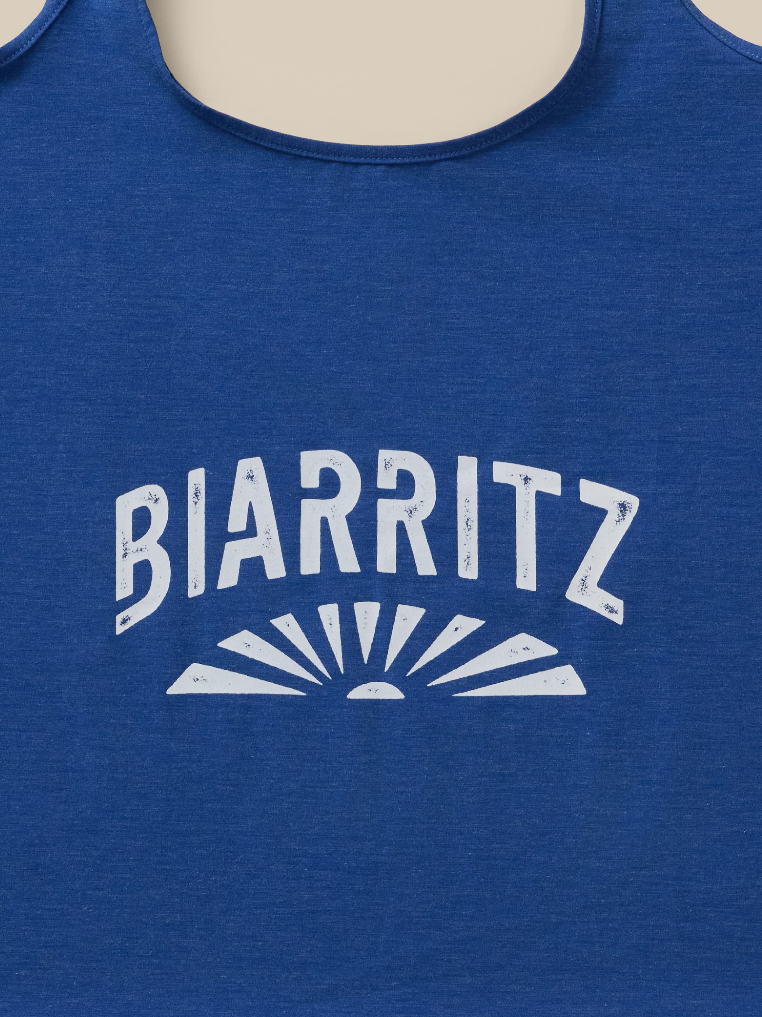 Blue tote bag with "Biarritz" graphic logo printed on it against a beige background