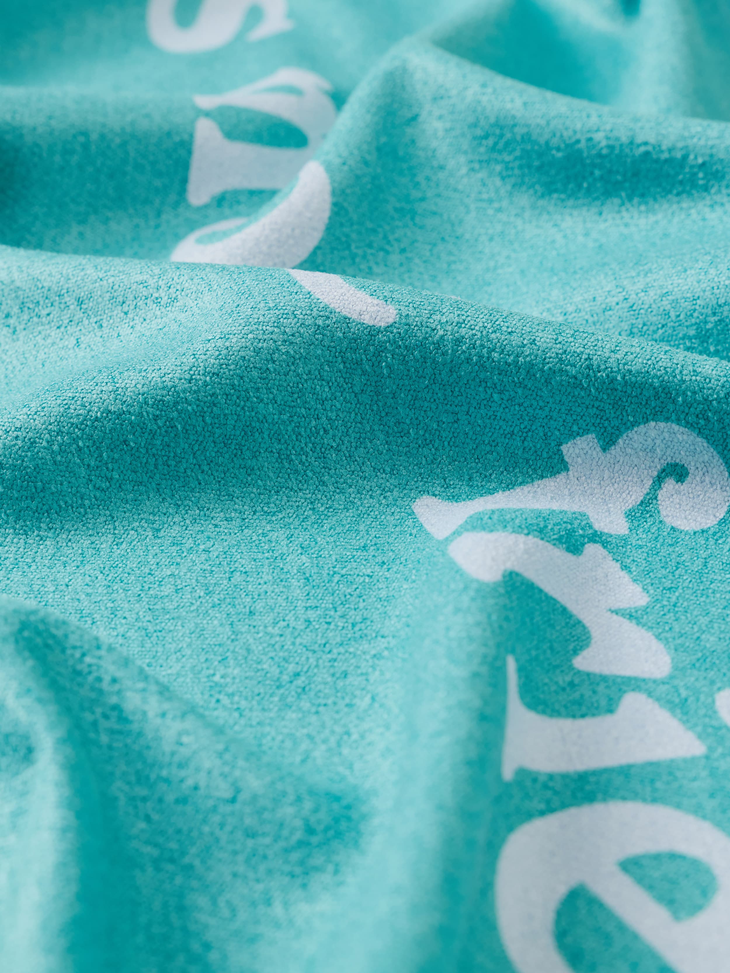 Close-up of teal towel with white text pattern