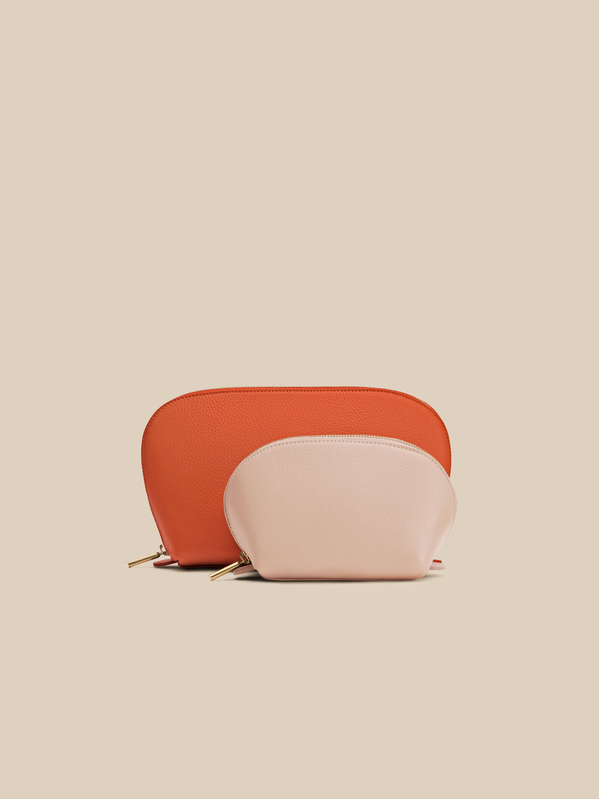 Two small leather pouches, one orange and one pink, on a beige background
