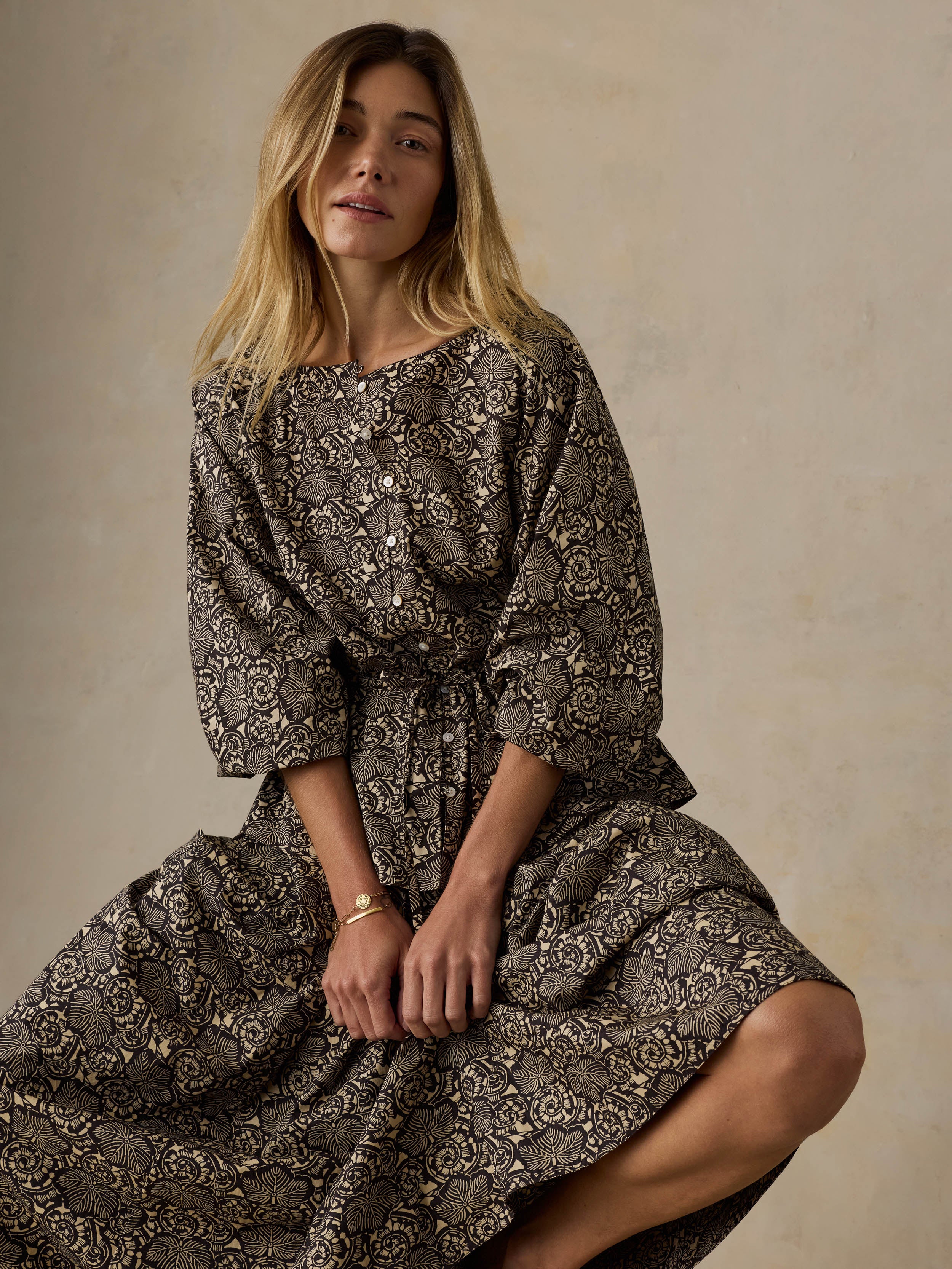 Woman wearing a floral patterned top and matching skirt against a beige background