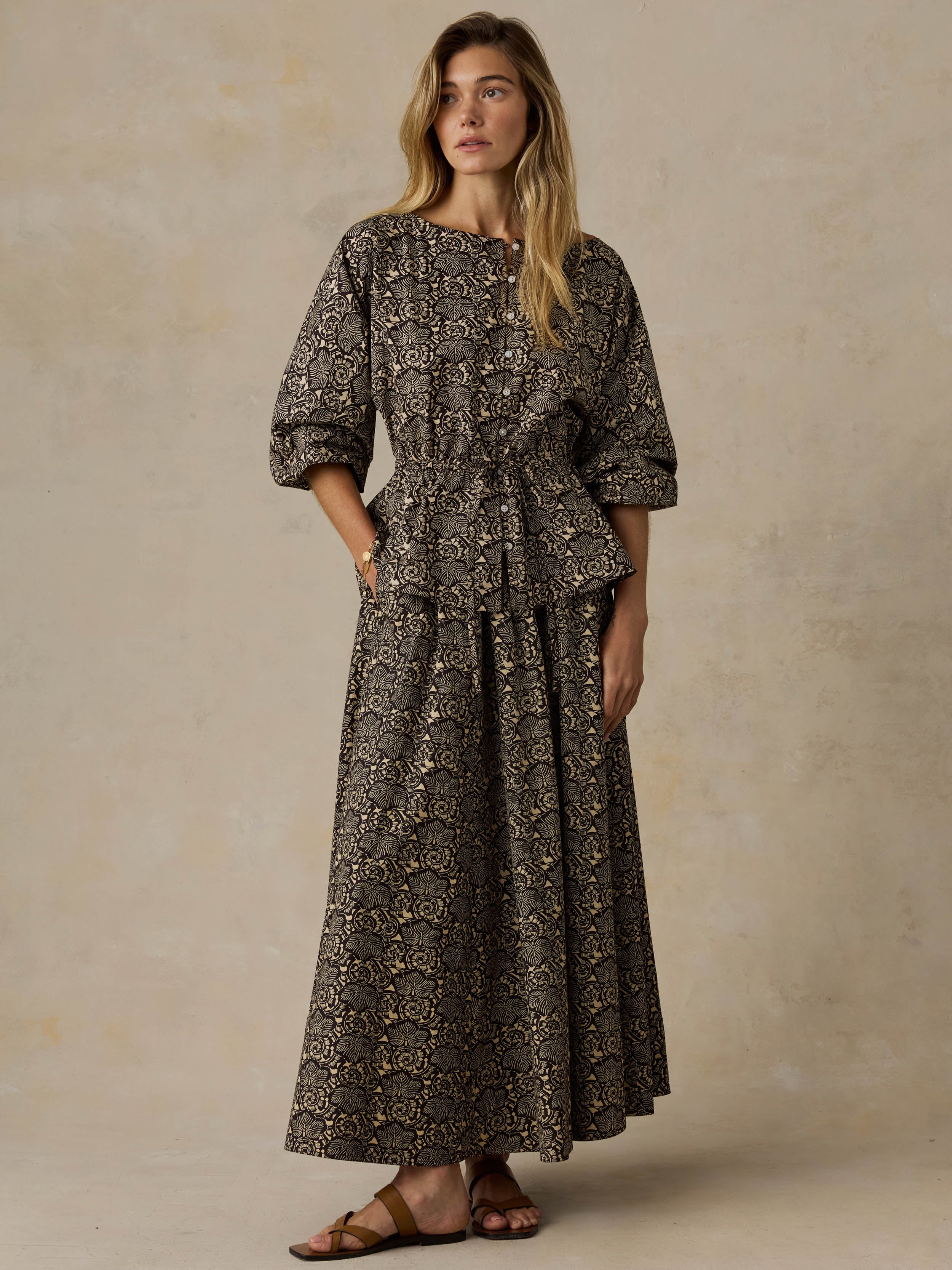 Woman wearing a floral patterned top and matching skirt against a beige background