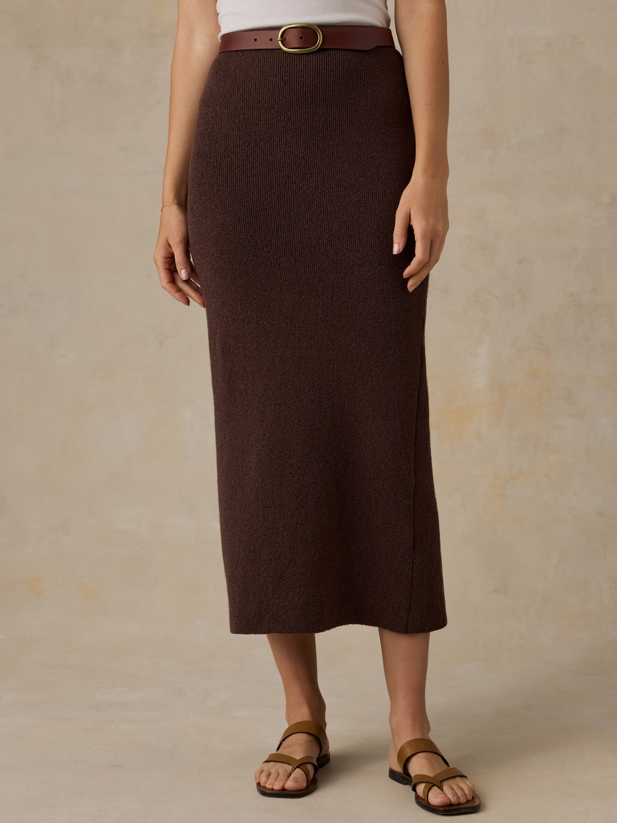 Woman wearing a brown knit skirt and a white top against a beige background, image 2 of 5