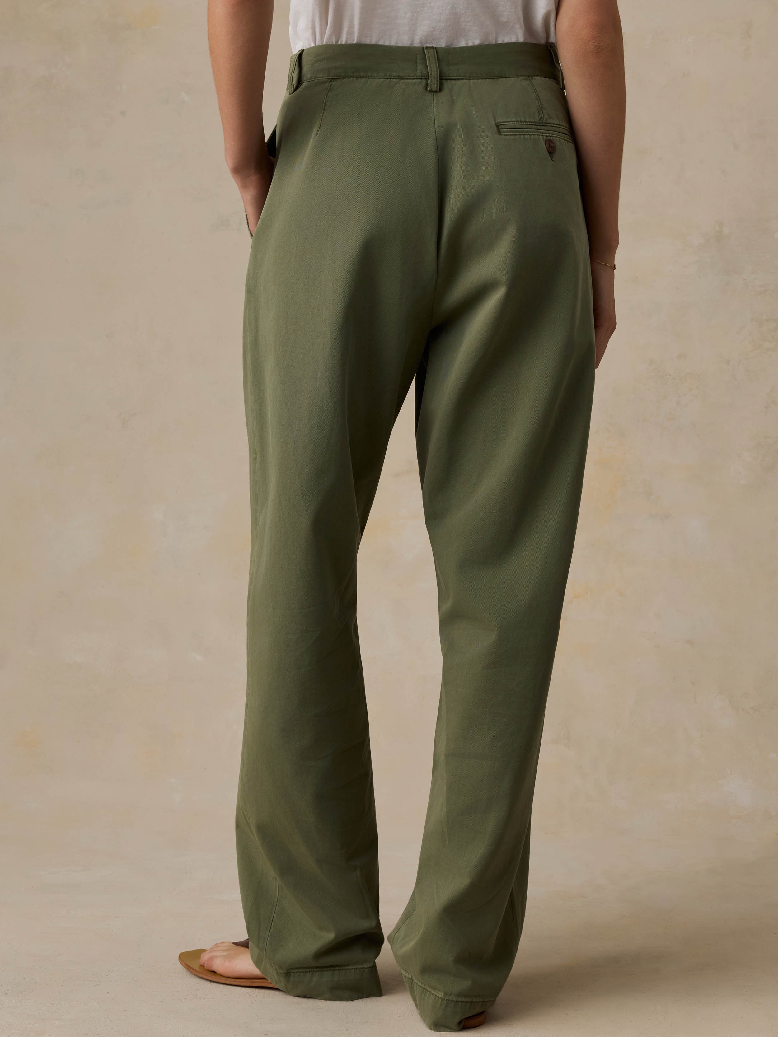 Woman wearing a white t-shirt and green pants against a beige background
