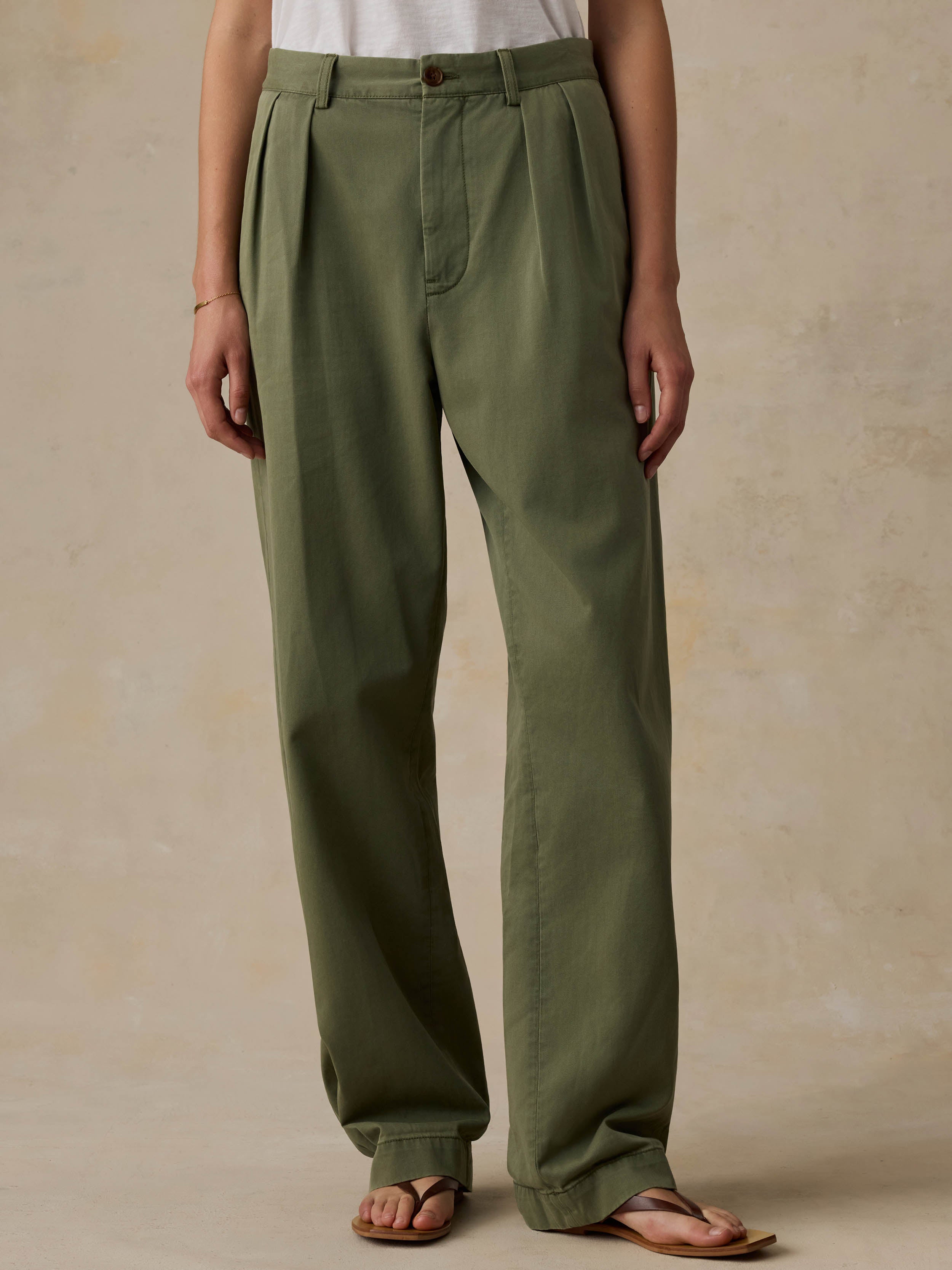 Woman wearing a white t-shirt and green pants against a beige background