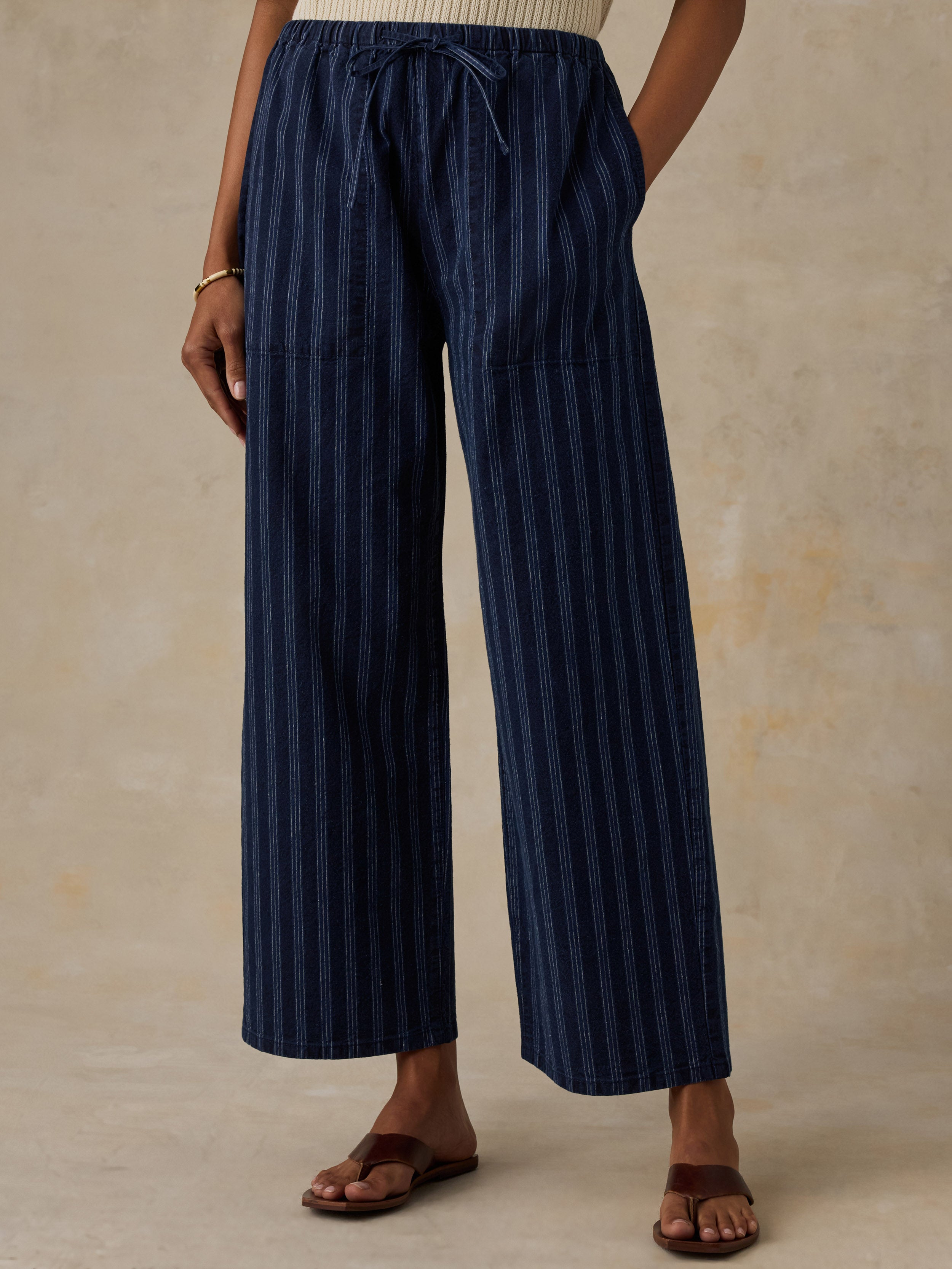 Woman wearing a blue striped pants against a beige background