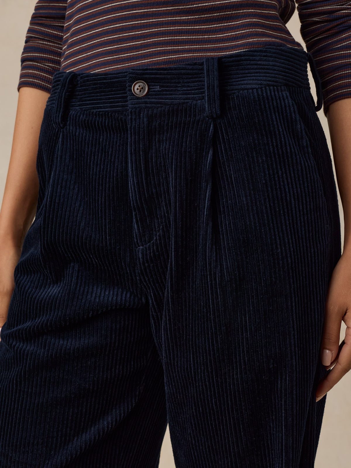 Close up of a woman wearing dark navy blue corduroy pants and a striped top, image 5 of 7