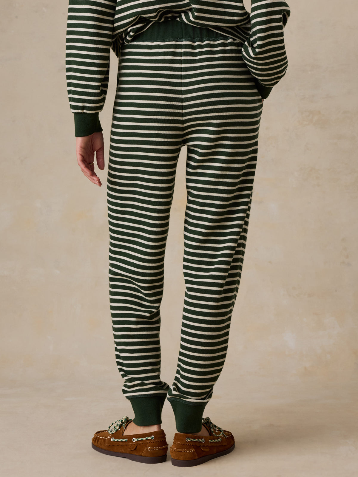 A woman viewed from behind wearing a green striped pajama set, image 4 of 6