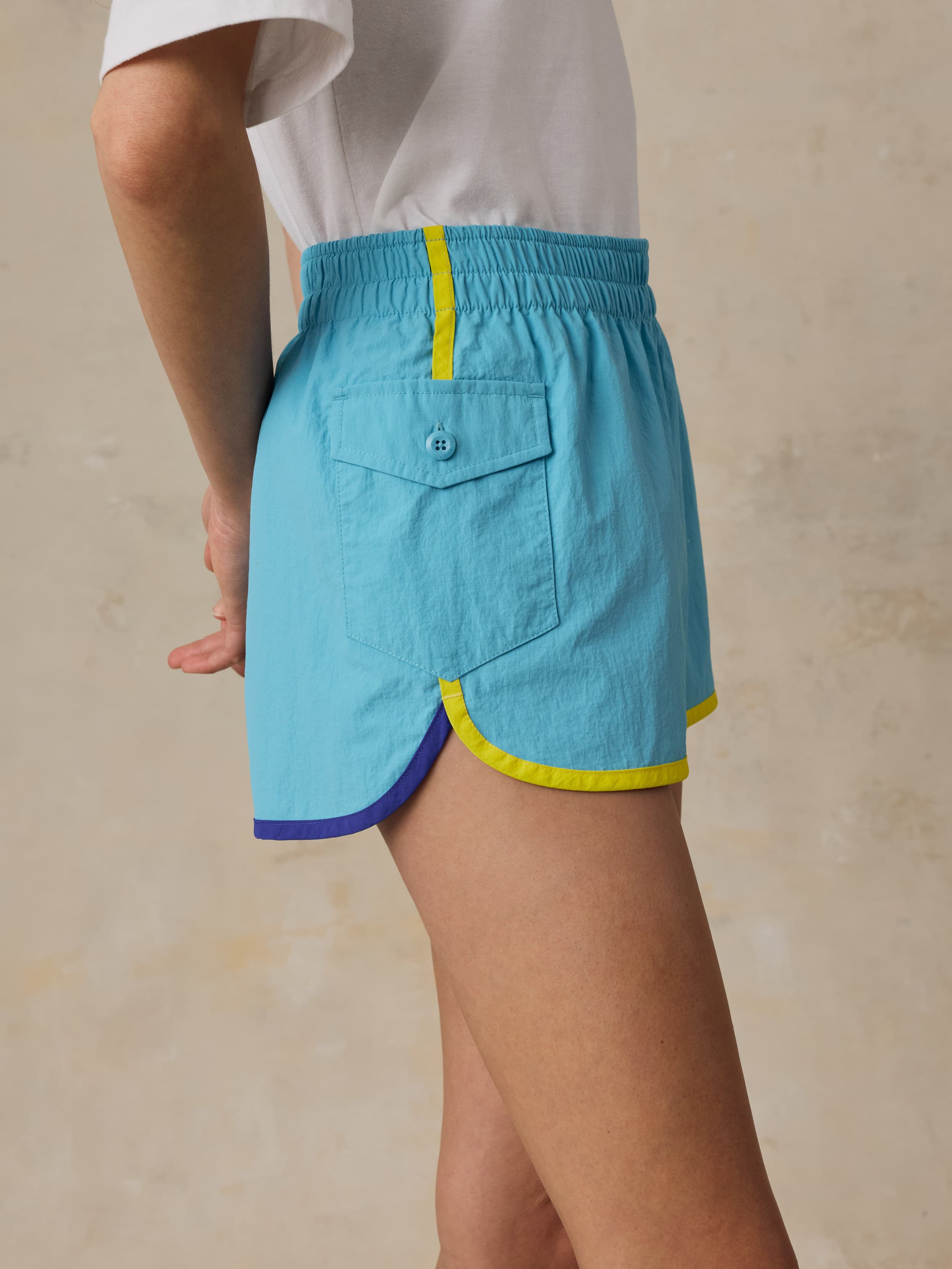 Woman wearing a white t-shirt and blue shorts on a beige background