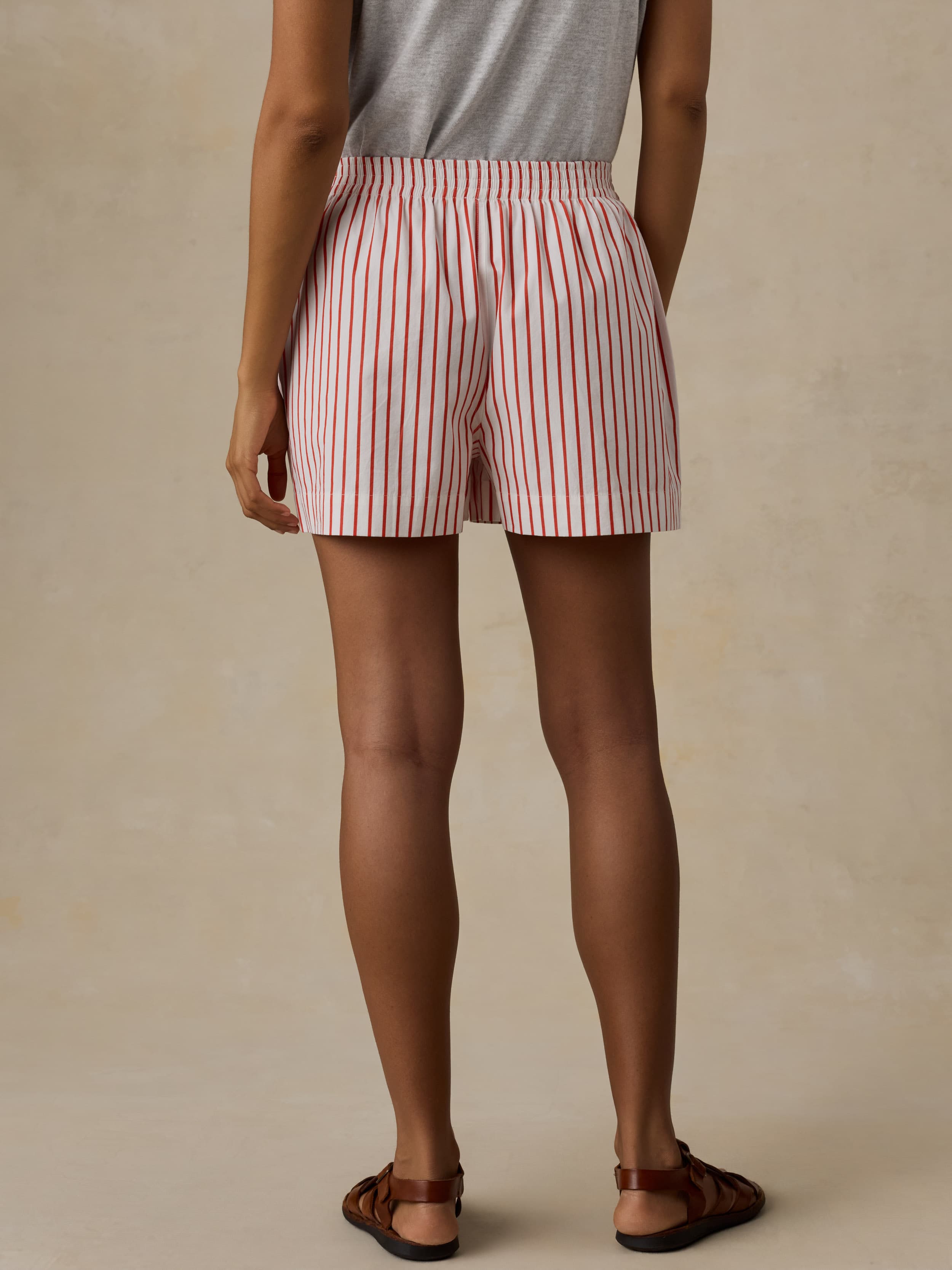Woman wearing red and white striped boxer shorts against a beige background