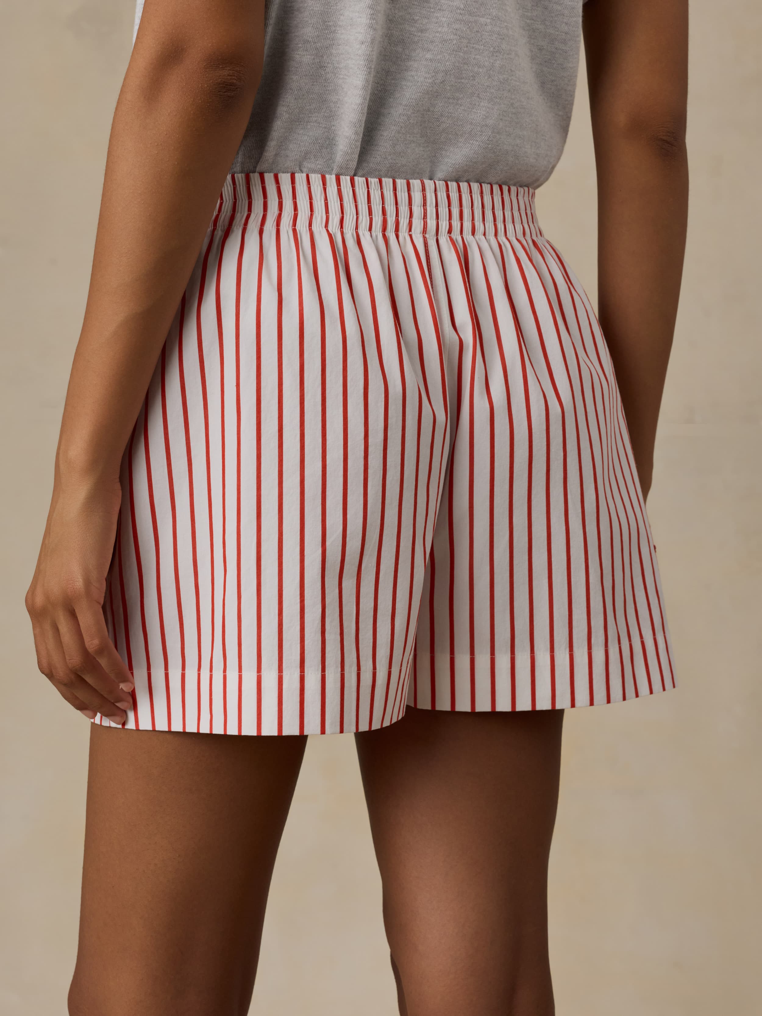 Red and white striped shorts worn by a woman on a beige background