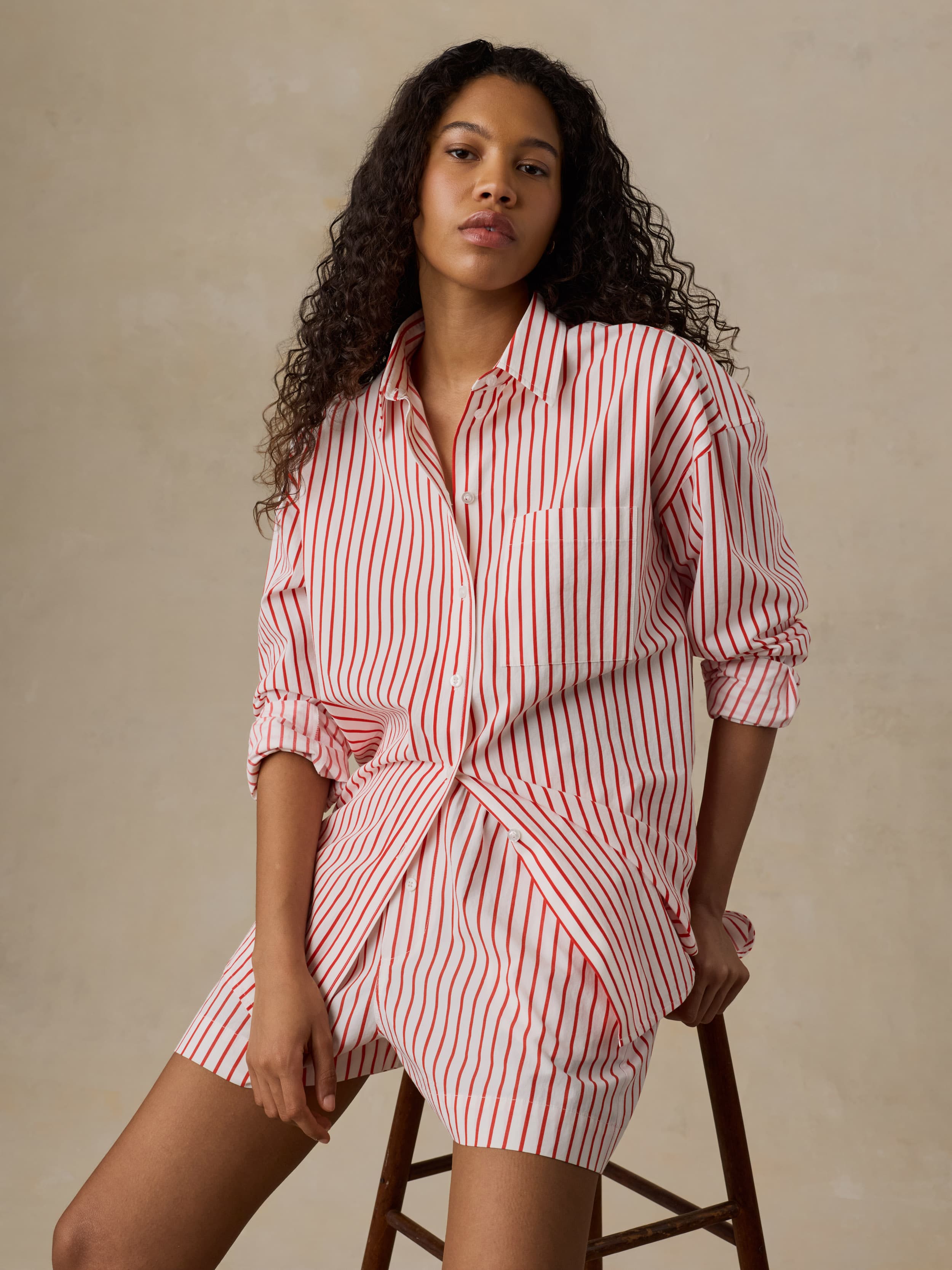 Woman wearing a red and white striped shirt and matching shorts against a beige background