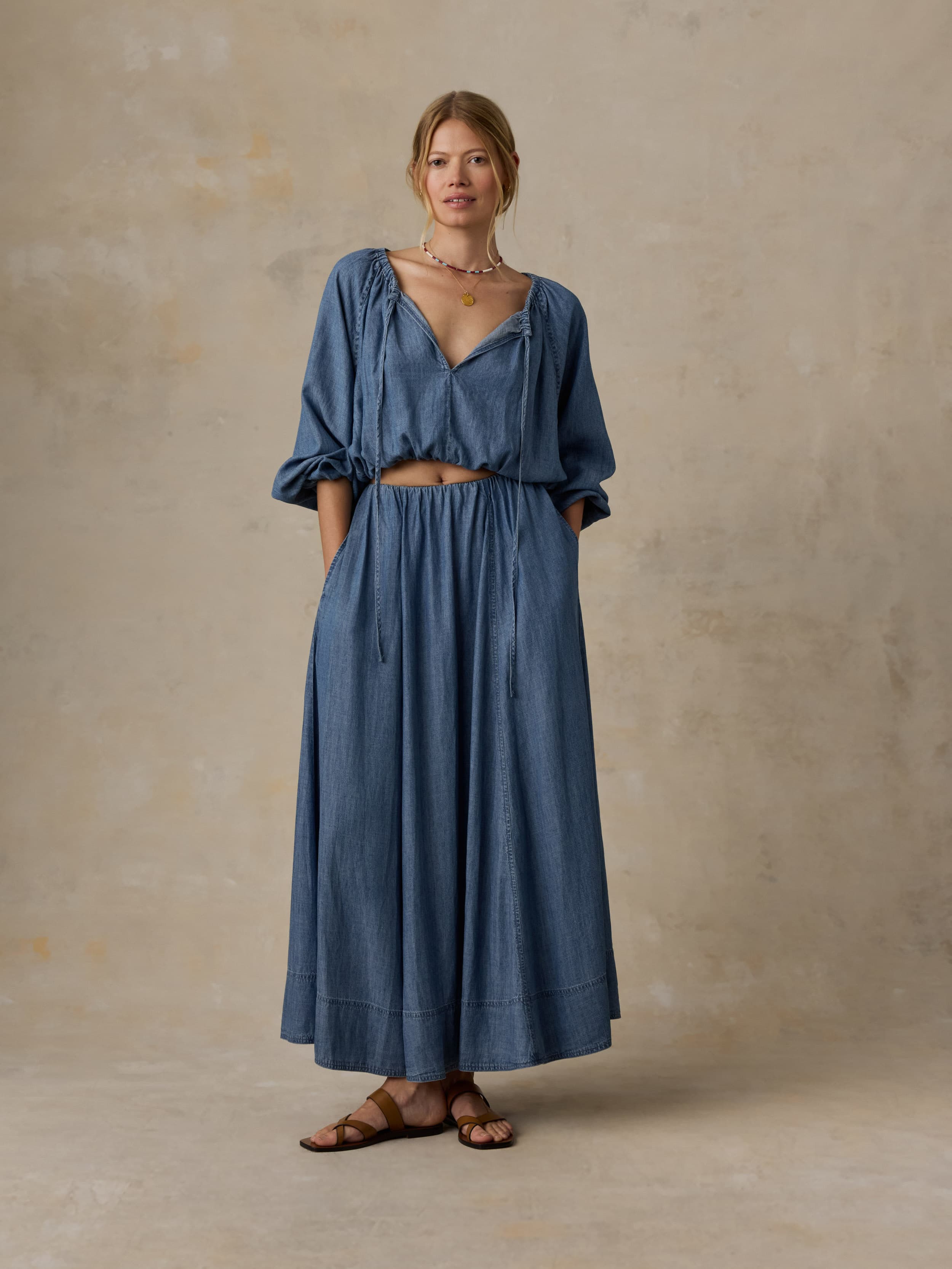 Woman wearing a denim top and matching skirt against a beige background