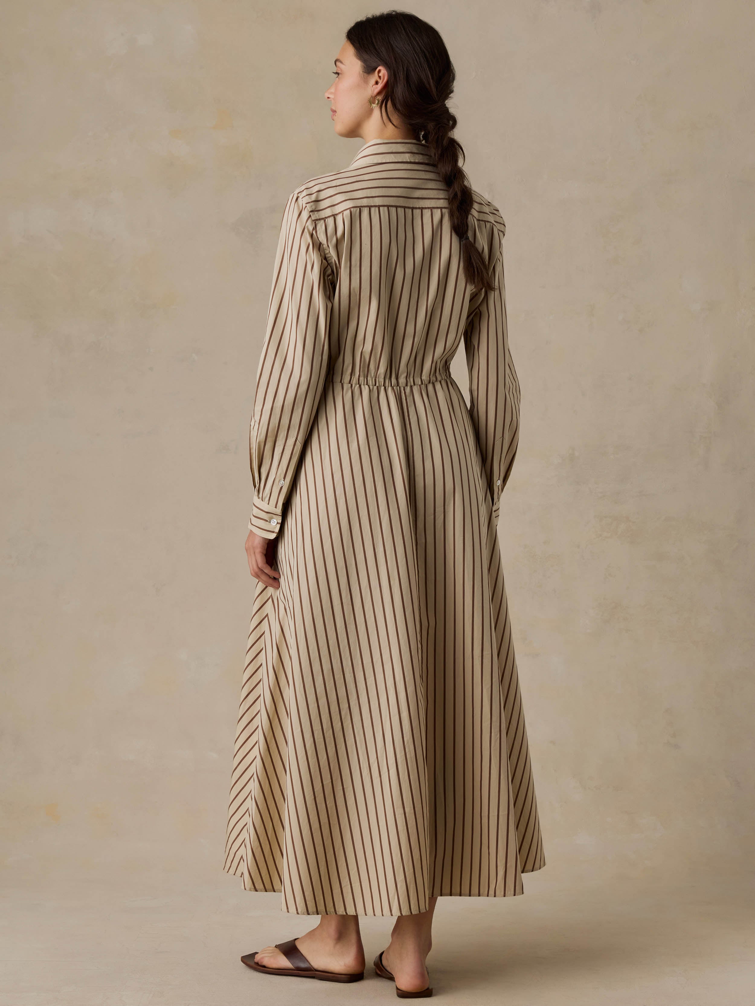 Woman wearing a tan striped dress against a beige background