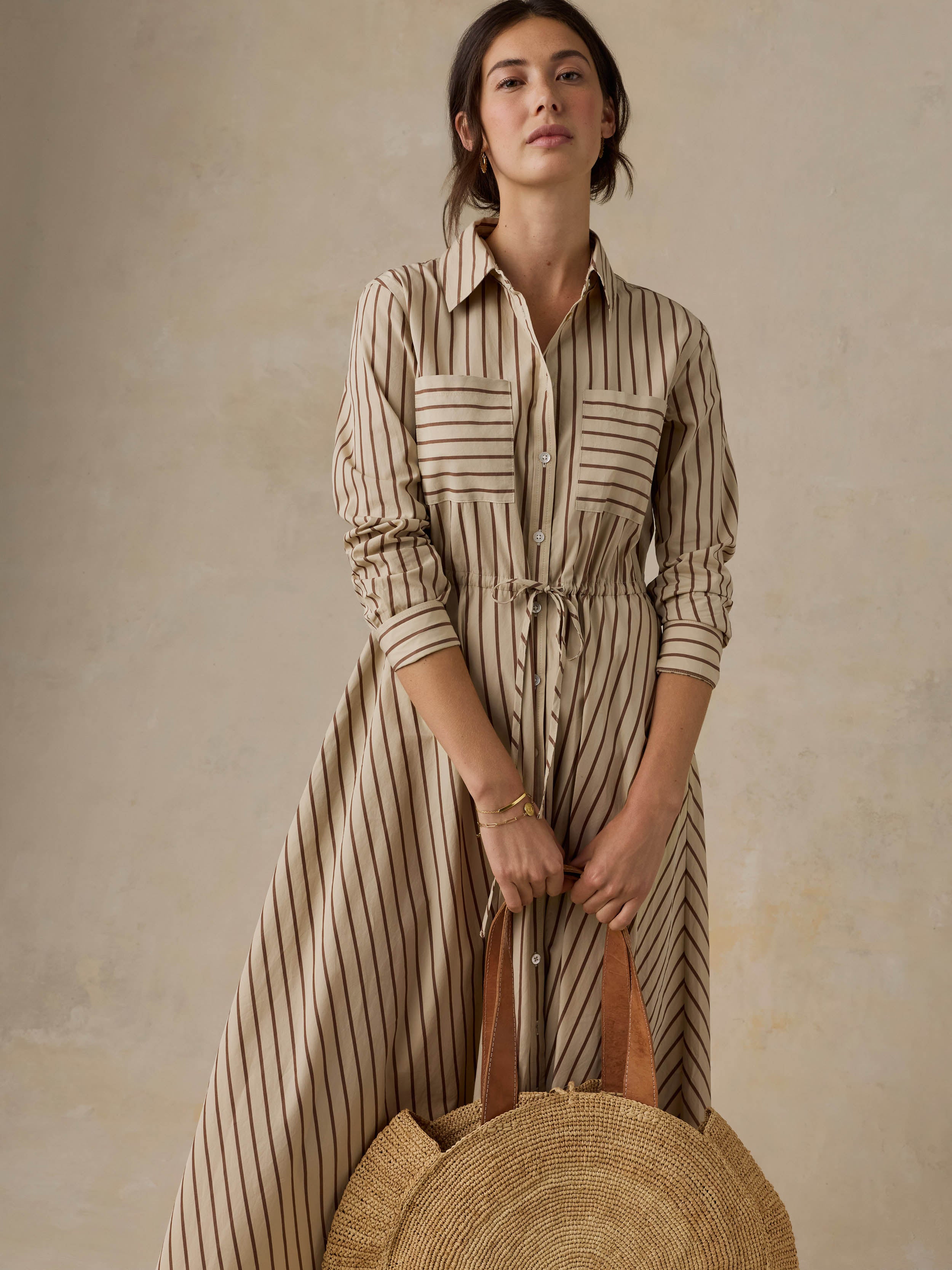 Woman wearing a tan striped dress against a beige background