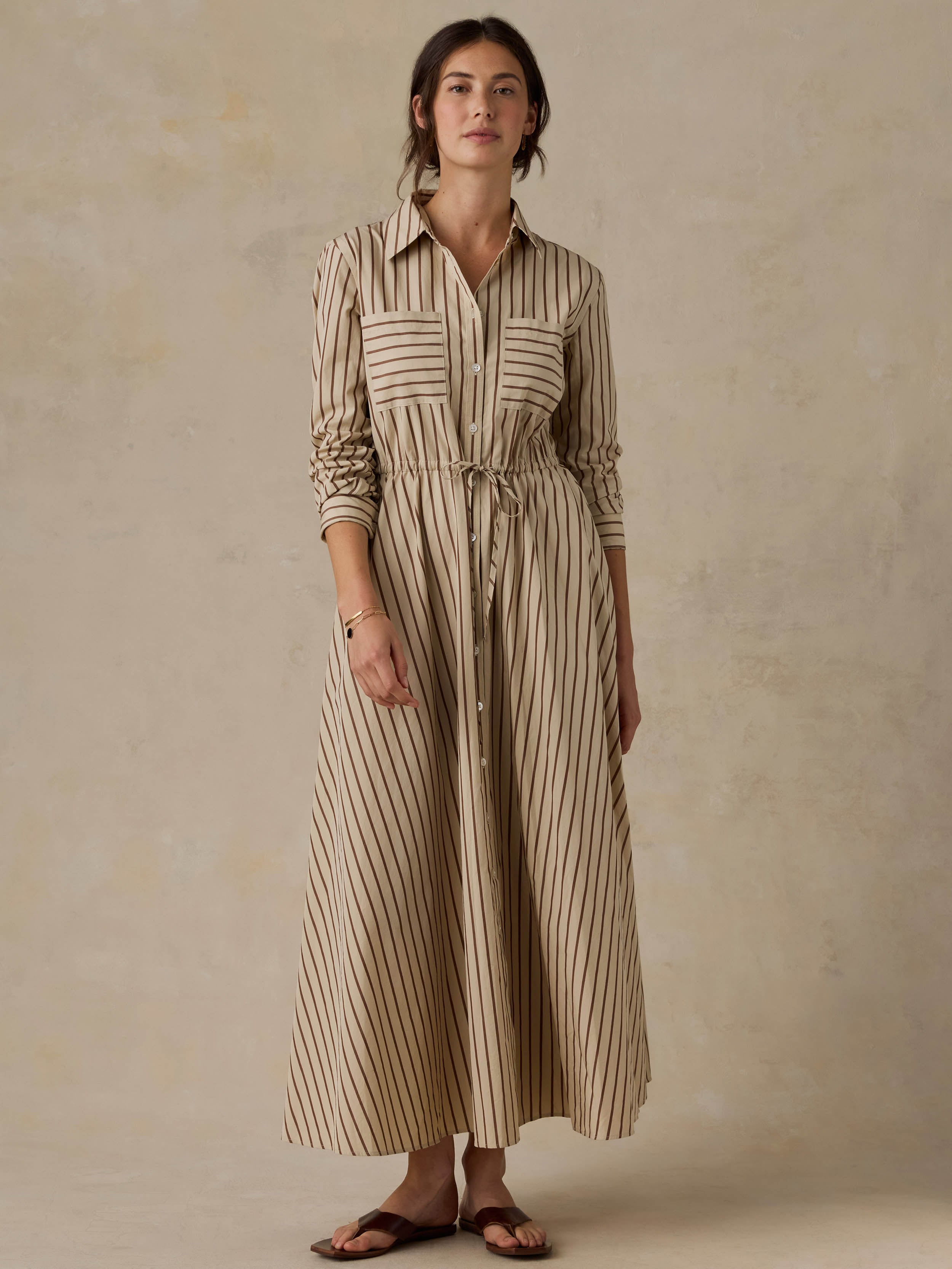 Woman wearing a tan striped dress against a beige background