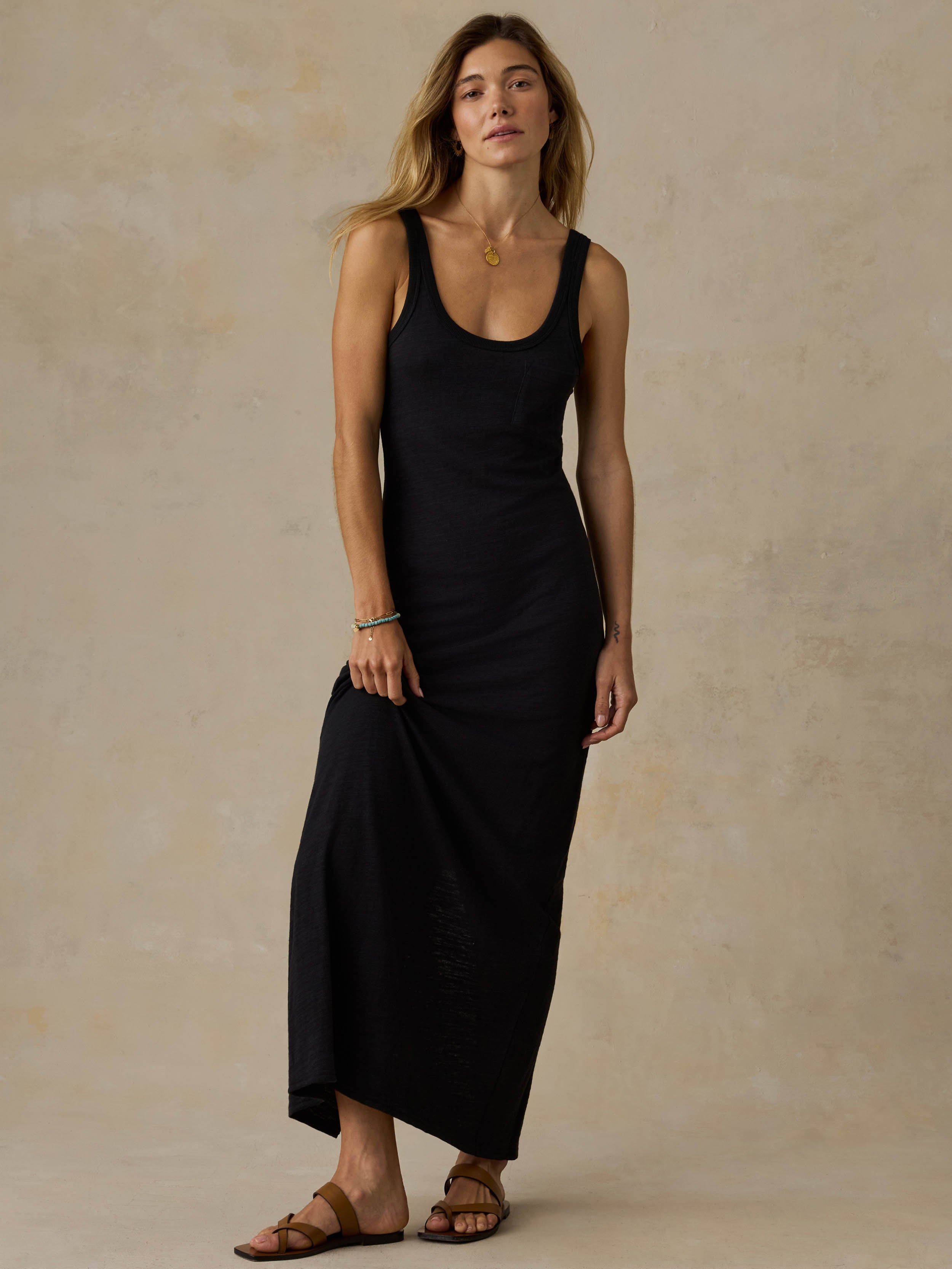Woman wearing a black sleeveless maxi dress against a beige background