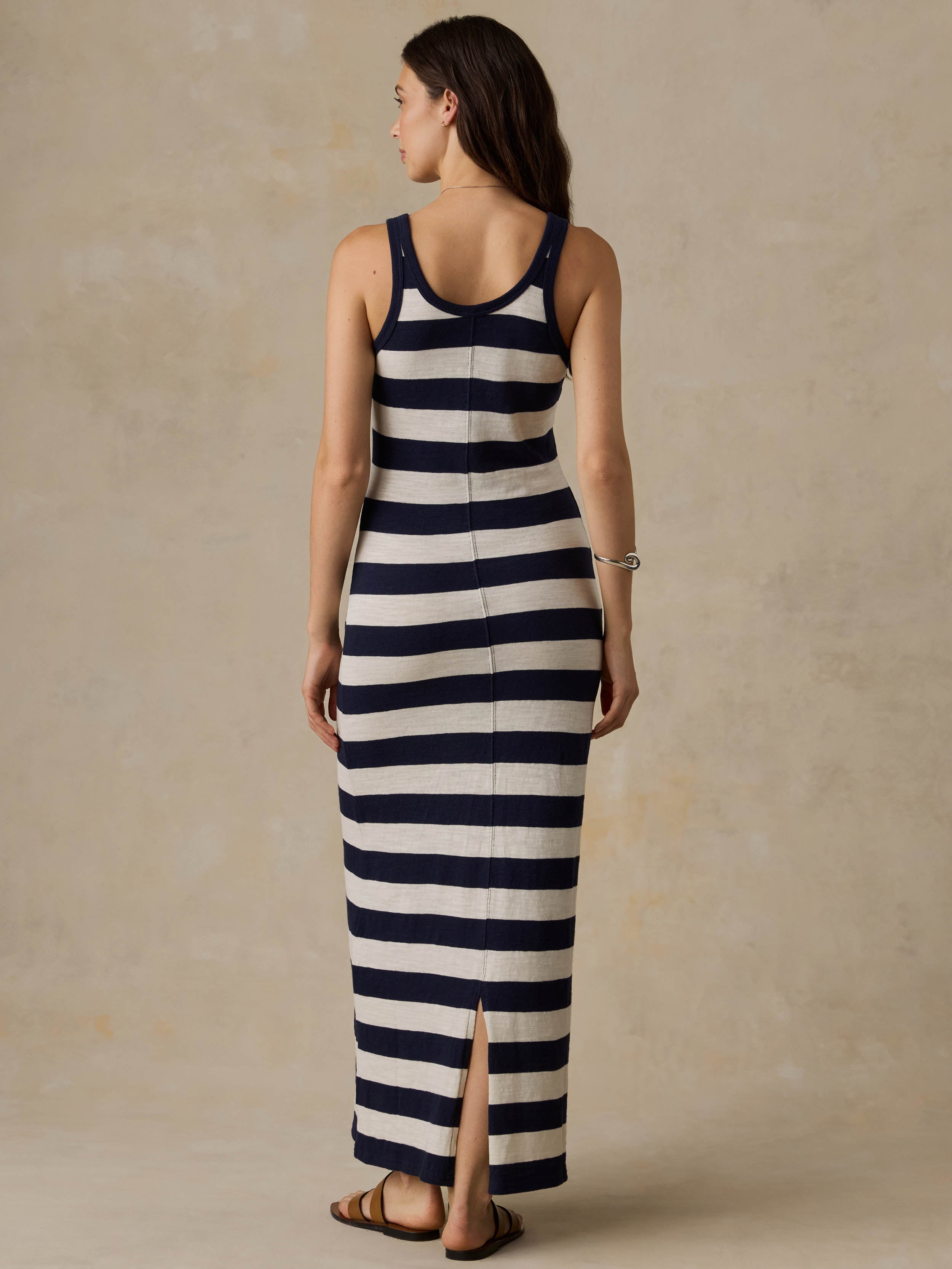 Woman wearing a navy and white striped dress against a beige background