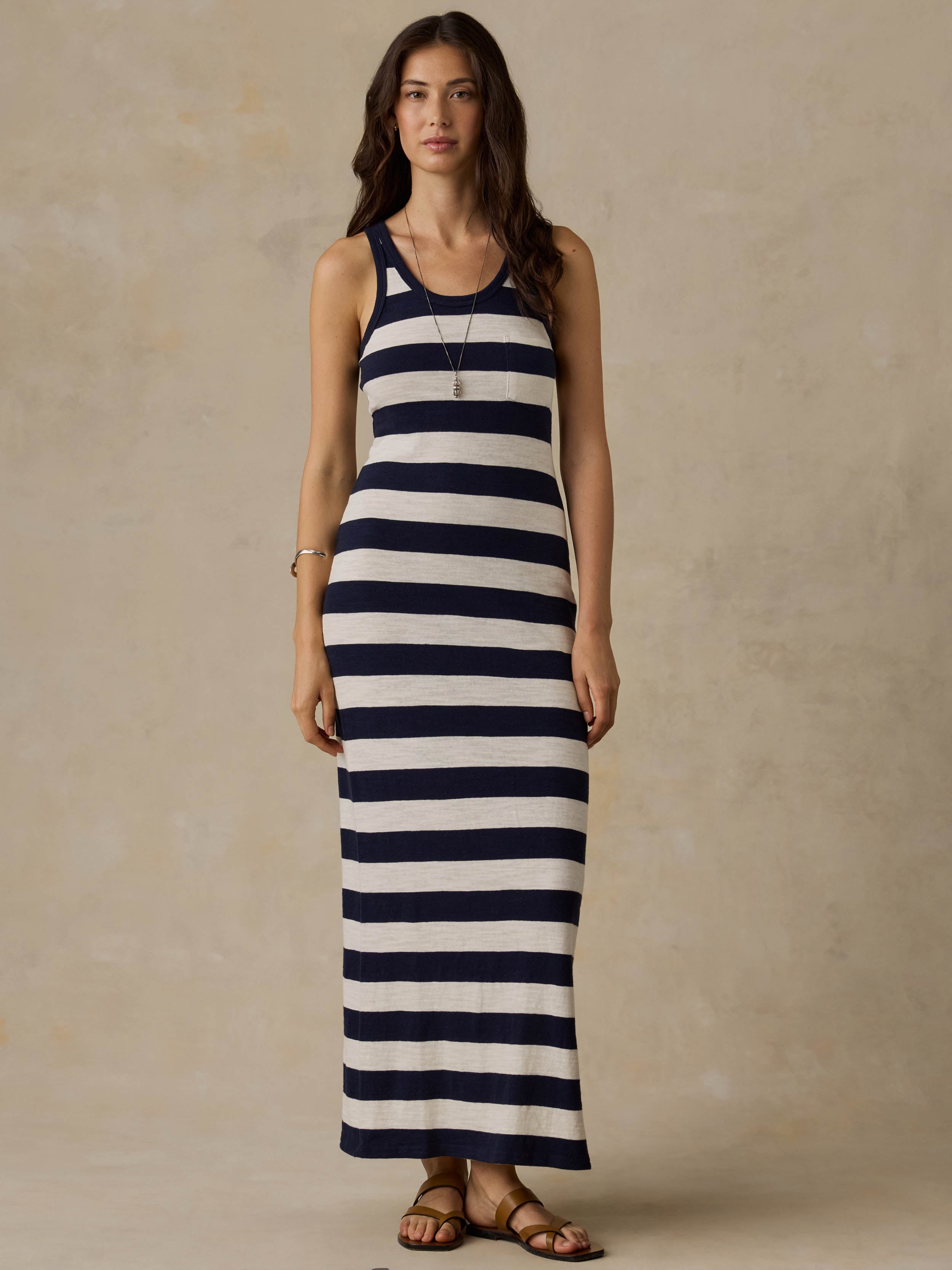 Woman wearing a navy and white striped dress against a beige background