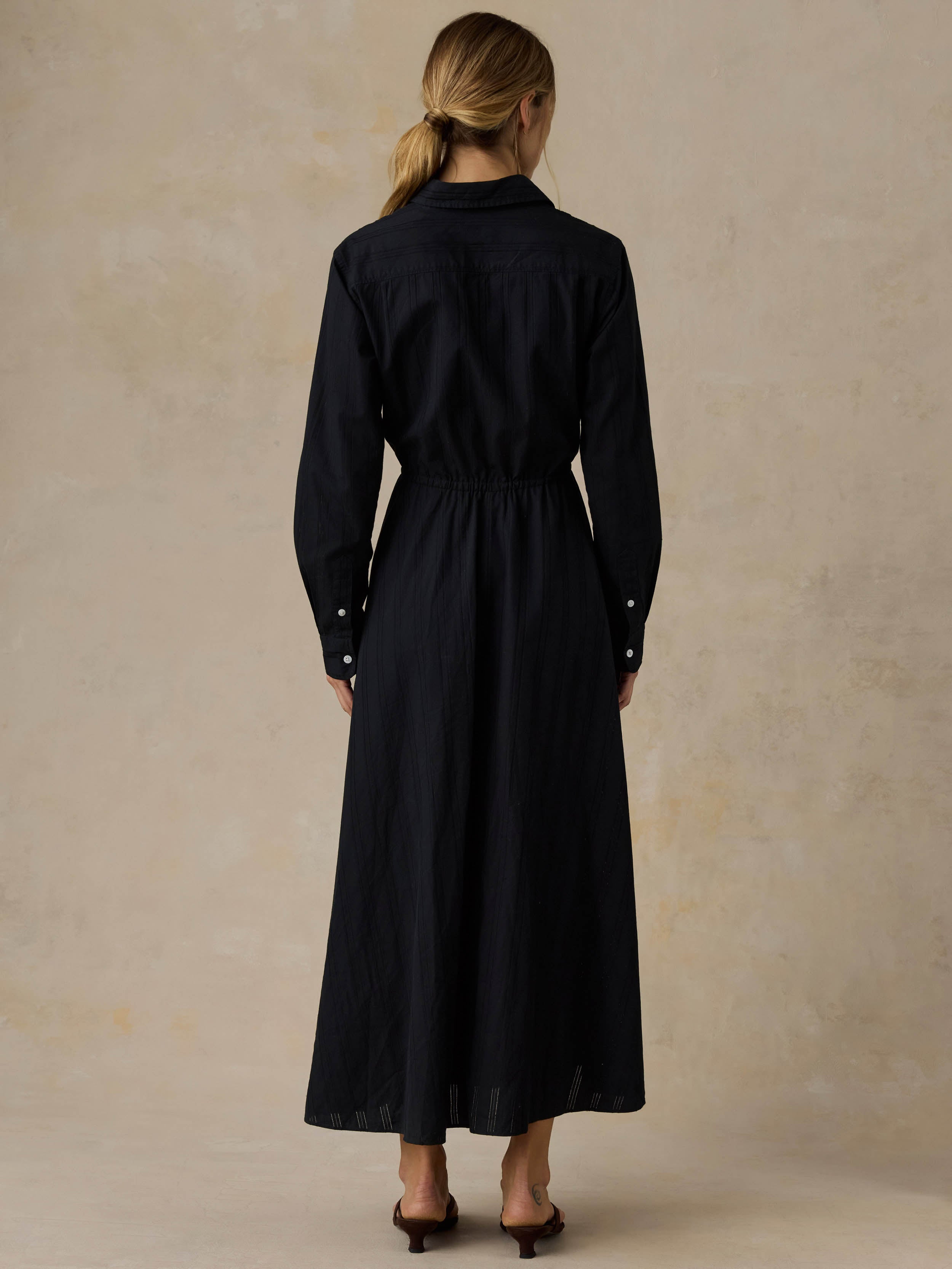 Woman wearing a black dress against a beige background