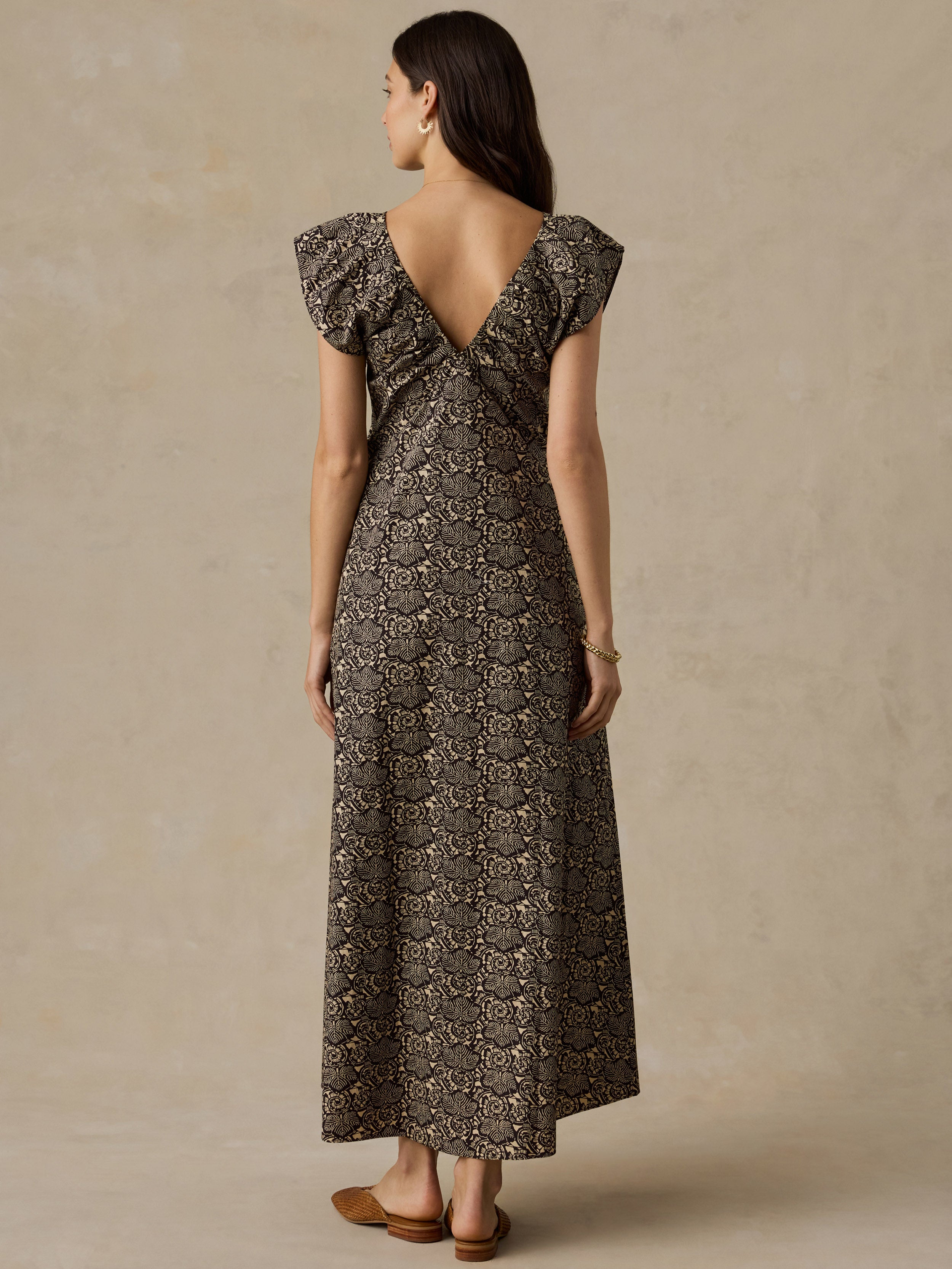 Woman wearing a black and beige floral printed dress against a beige background