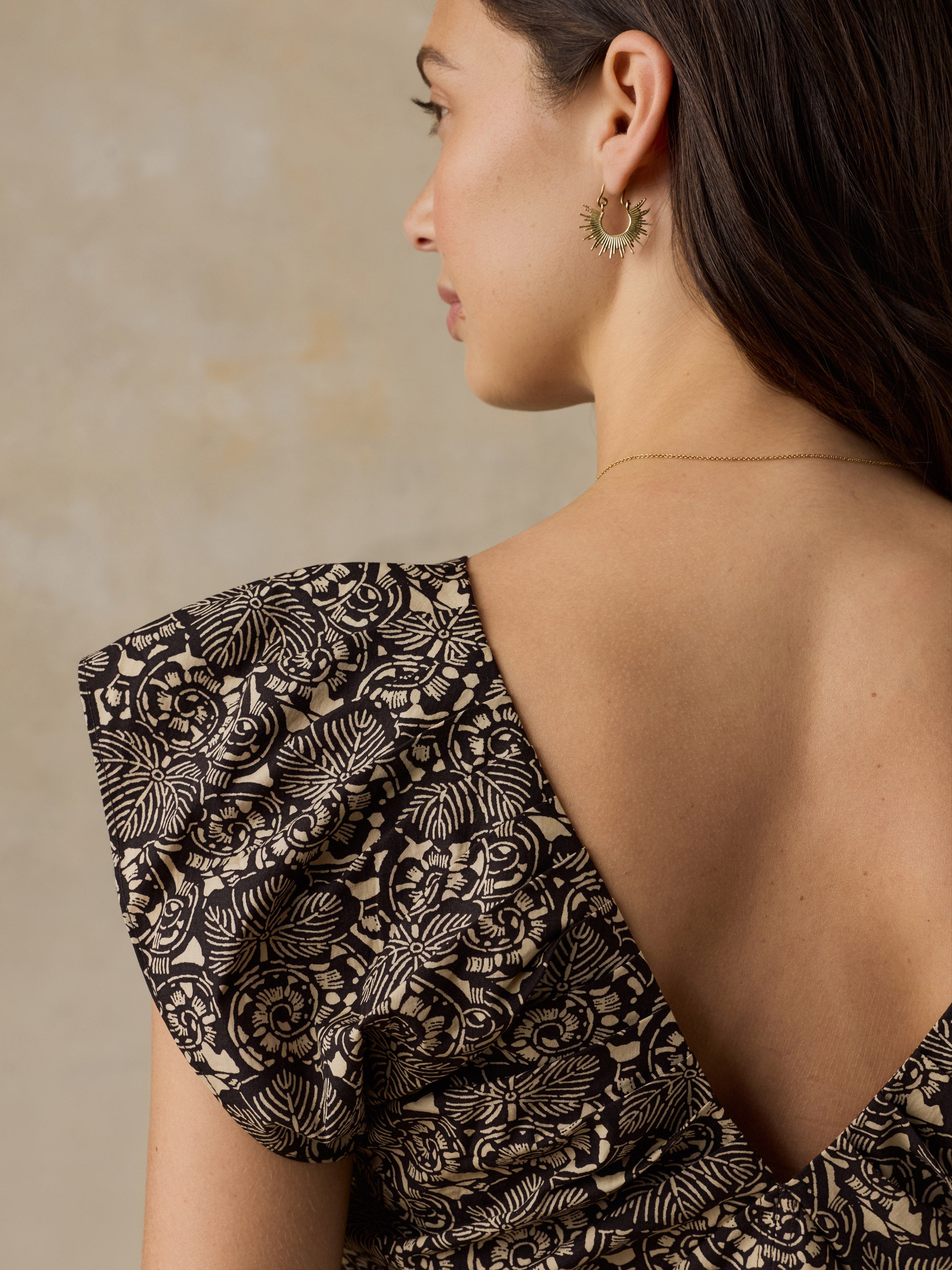 Woman wearing a black and beige floral printed dress against a beige background