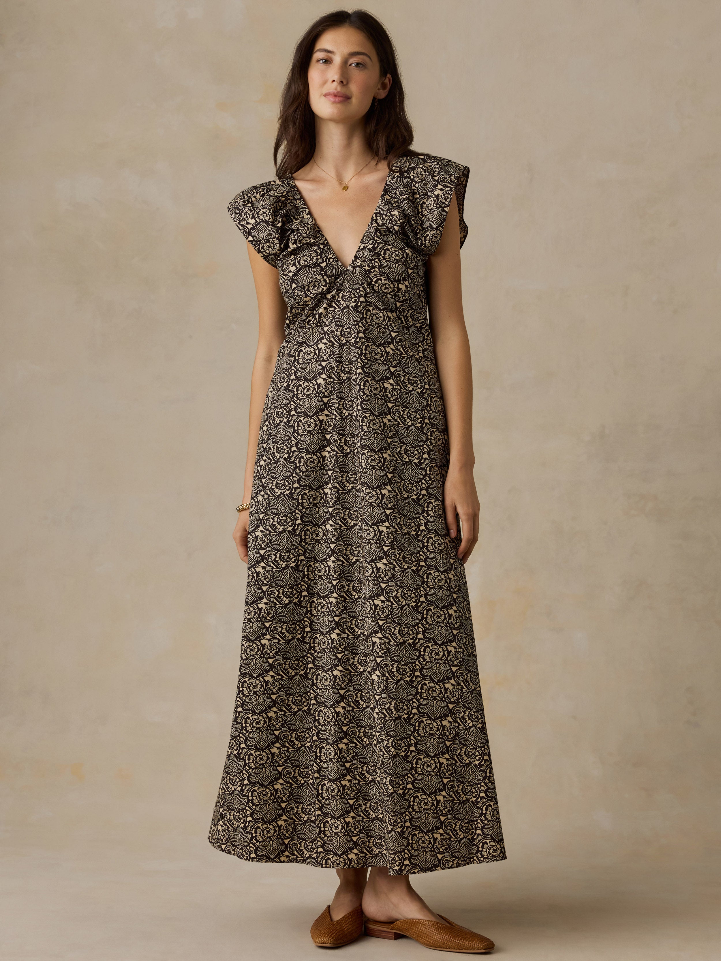 Woman wearing a black and beige floral printed dress against a beige background