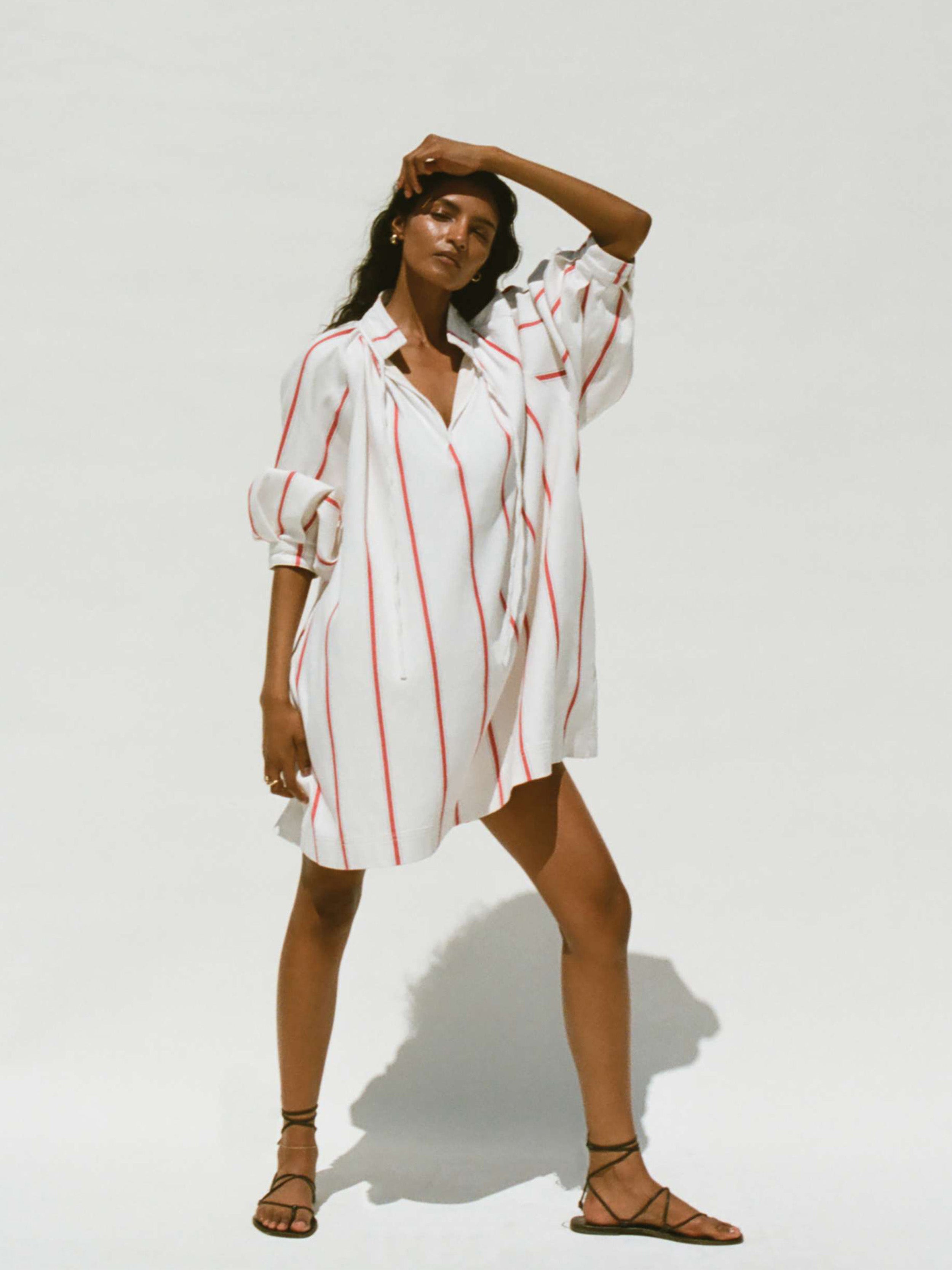 Woman wearing a white dress with red stripes against a white background