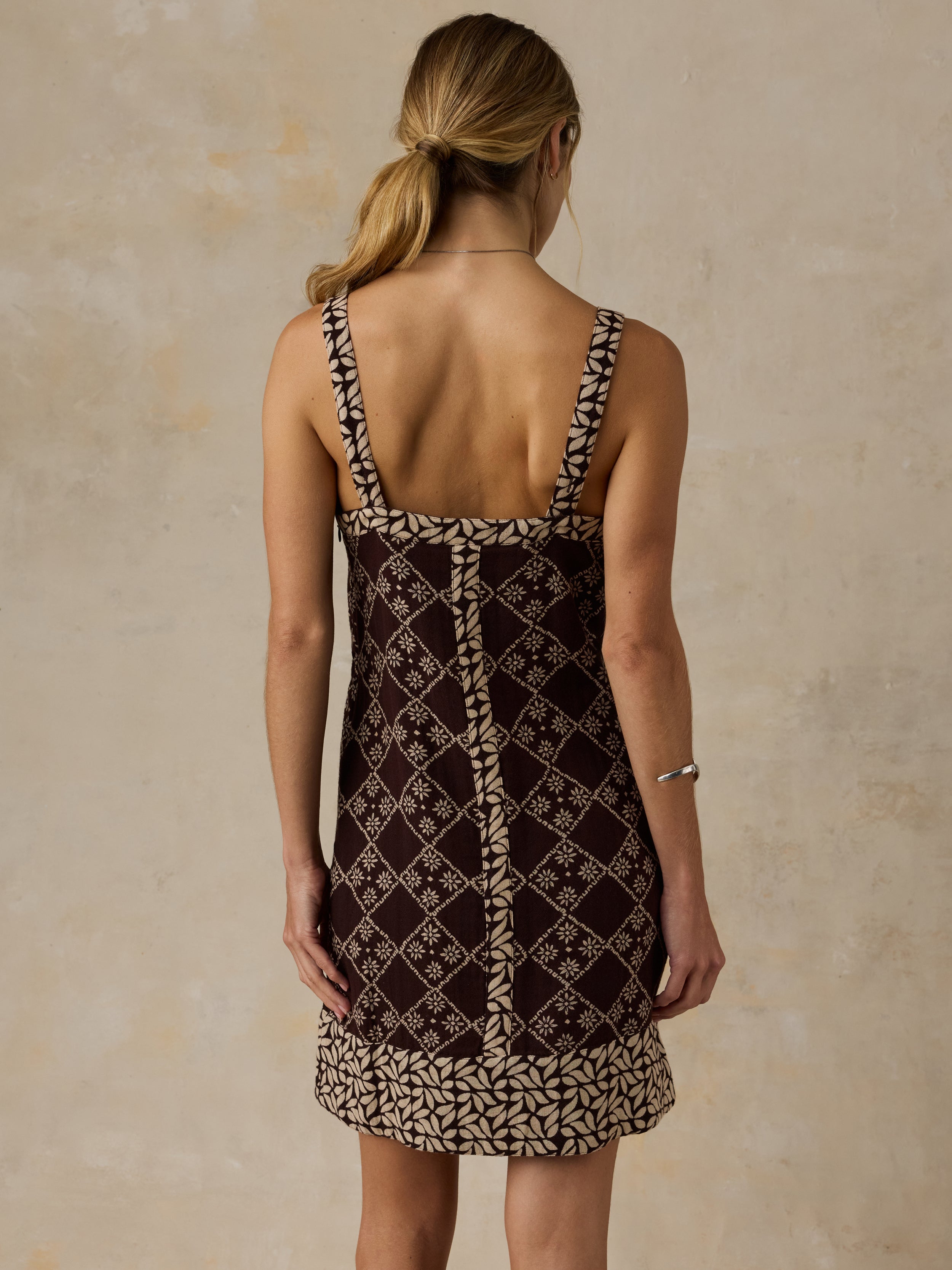 Woman wearing a brown patterned dress against a beige background