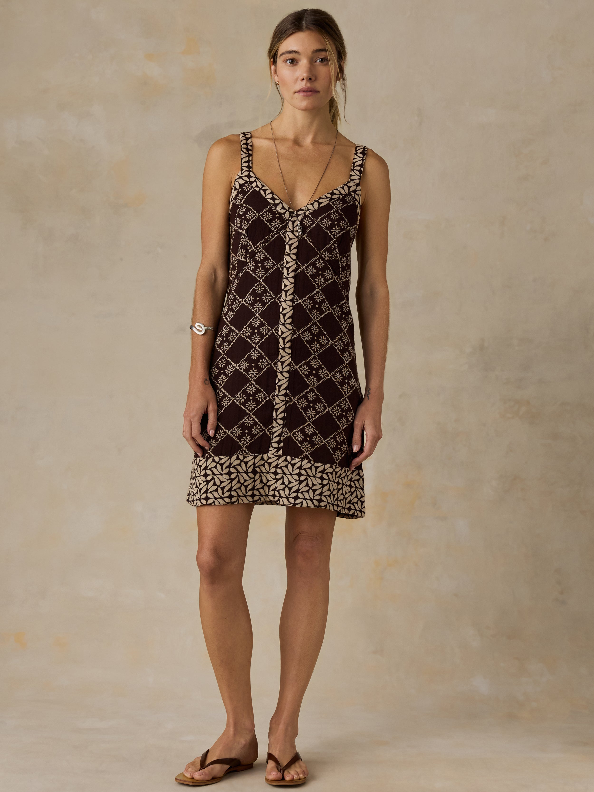 Woman wearing a brown patterned dress against a beige background