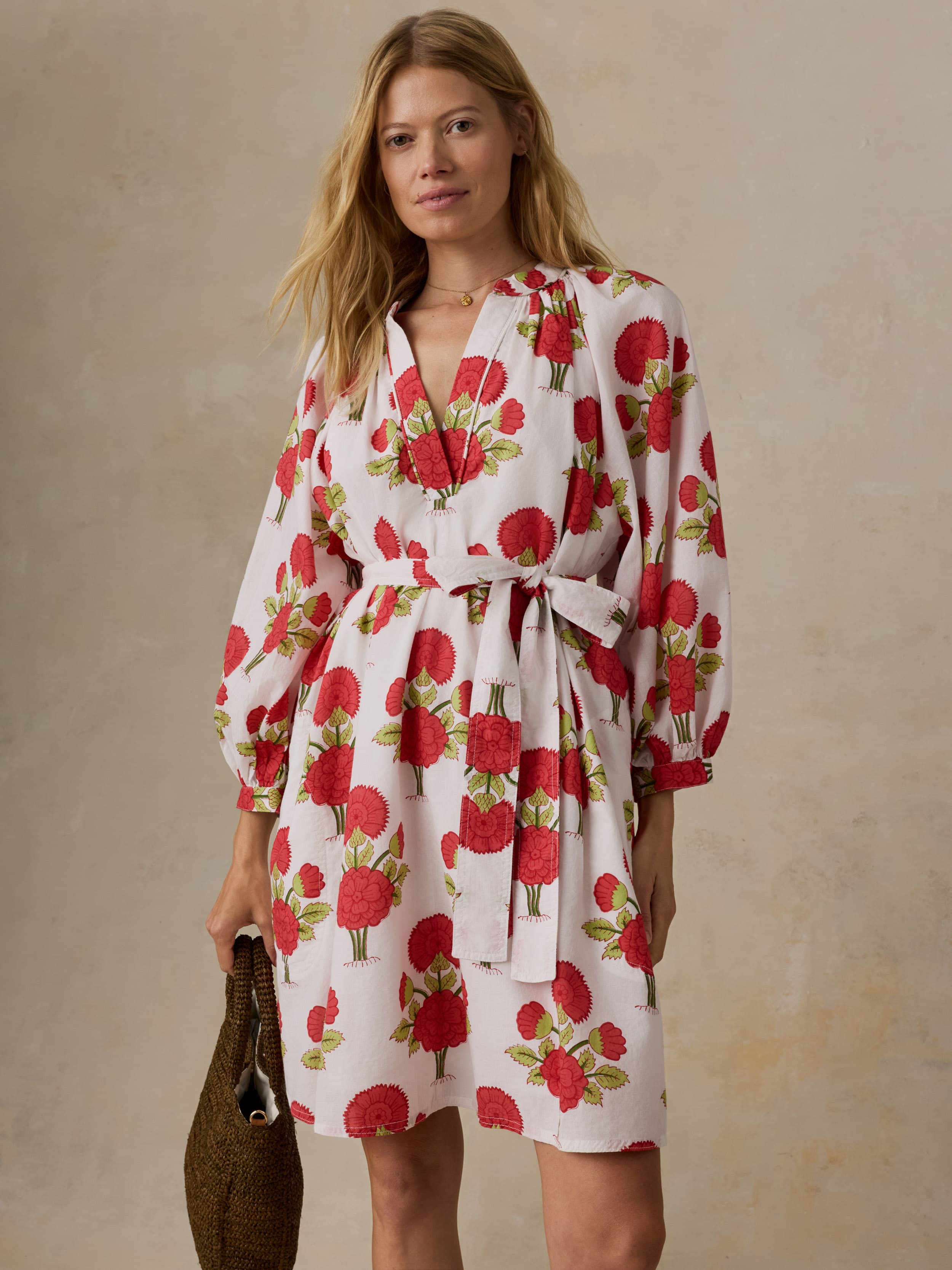 Woman wearing a white dress with red floral patterns on a beige background