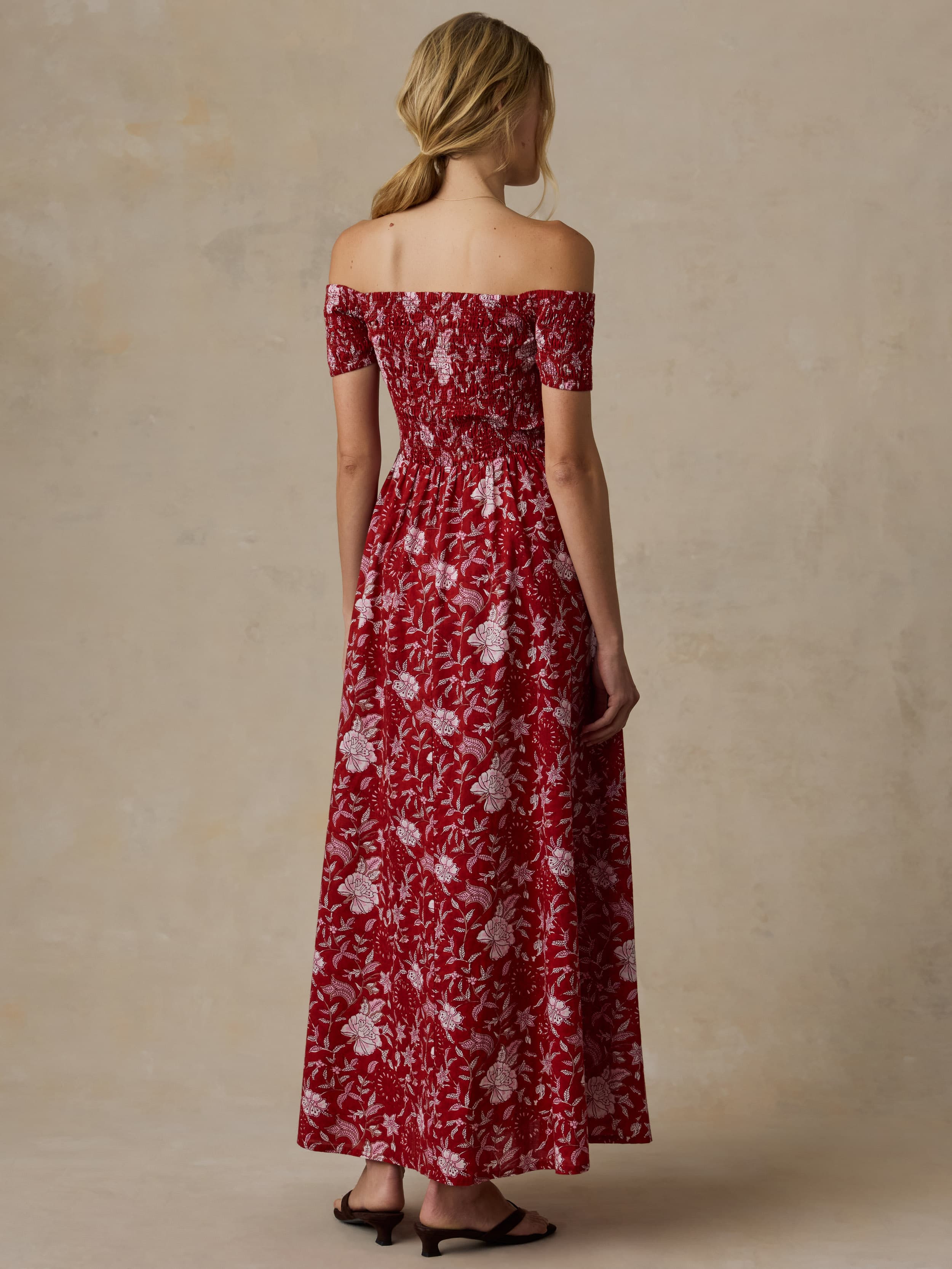 Woman wearing a red floral off-shoulder dress against a beige background