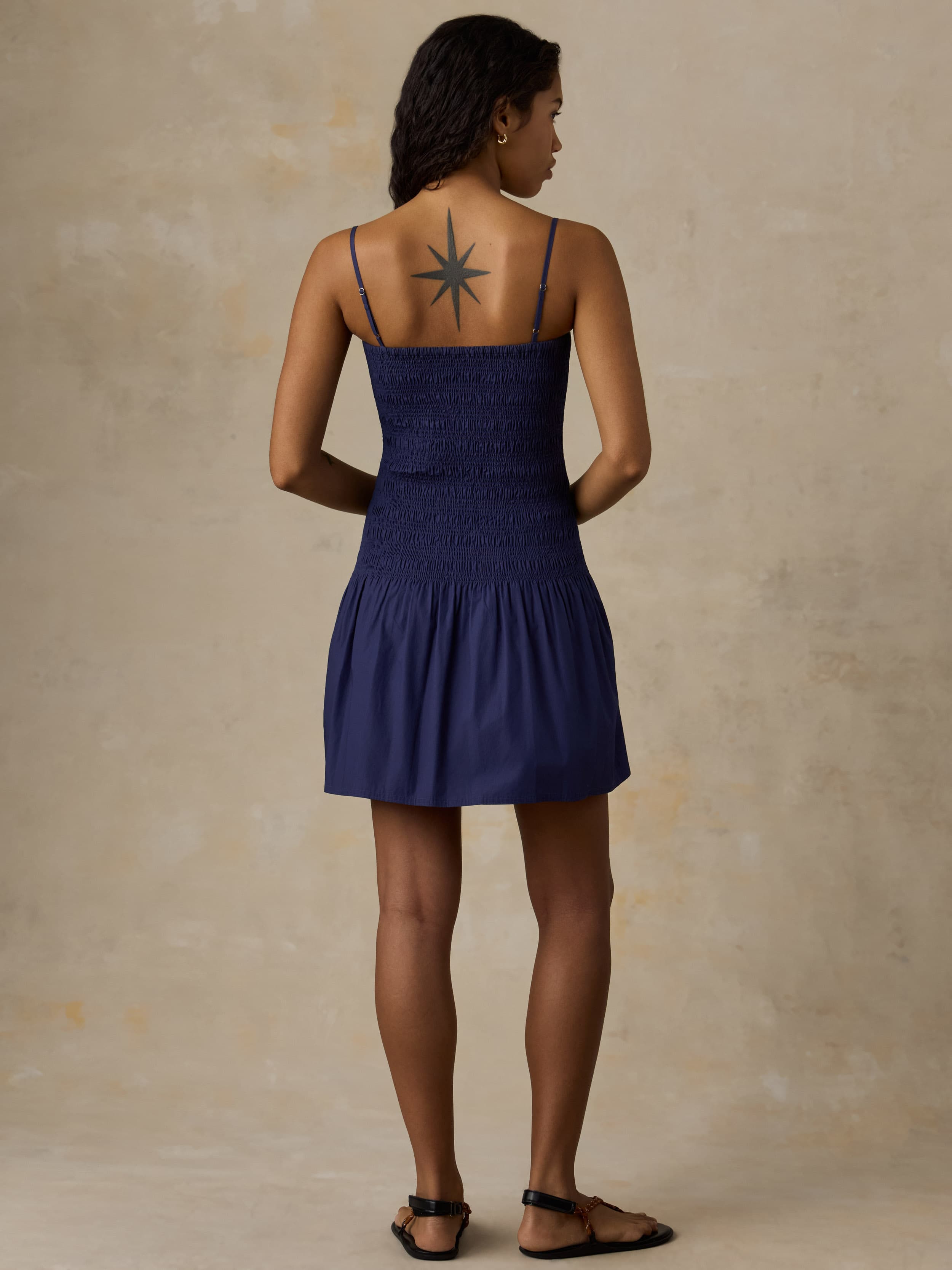 Woman wearing a navy blue dress against a beige background