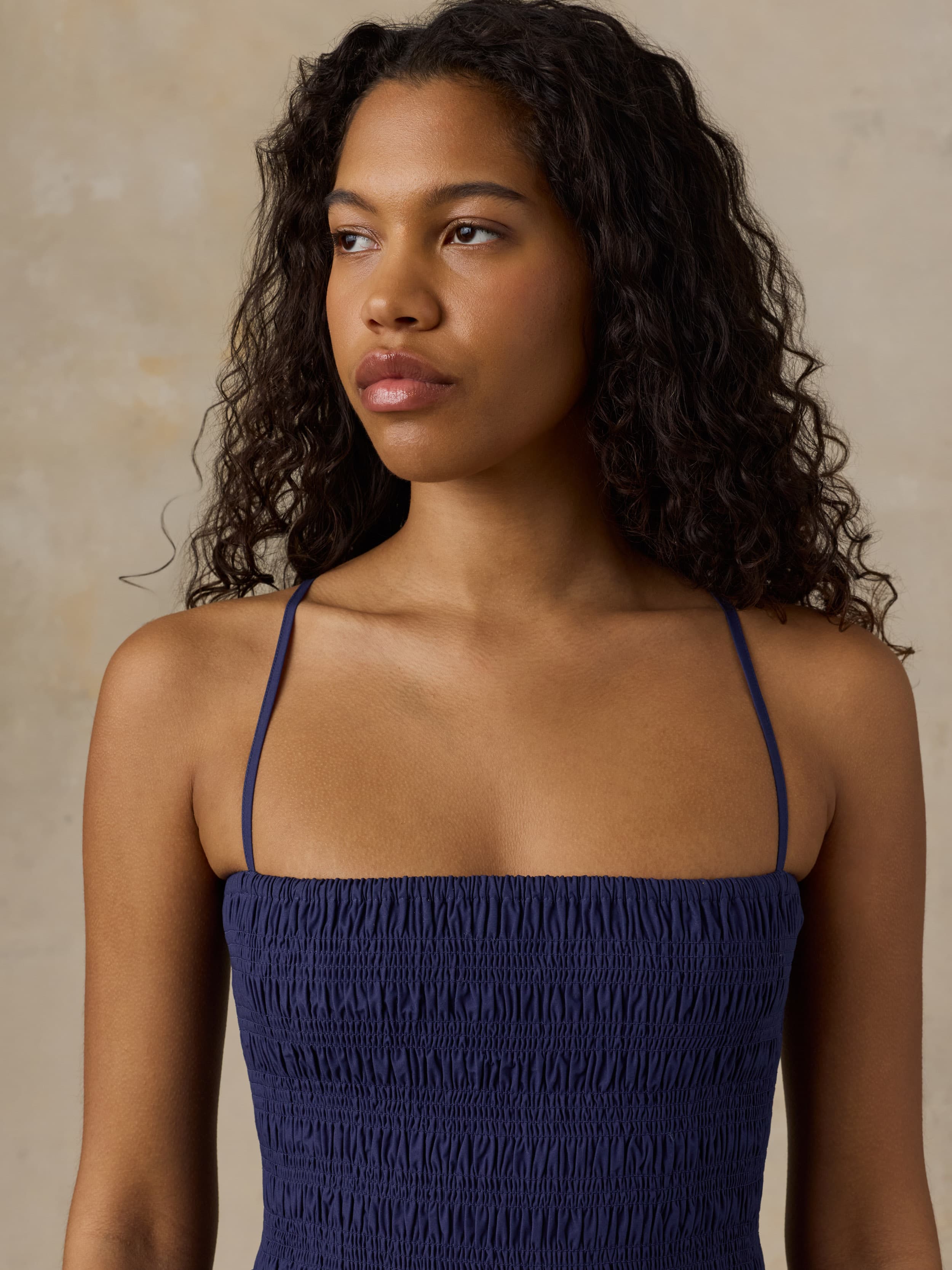 Woman wearing a navy blue dress against a beige background