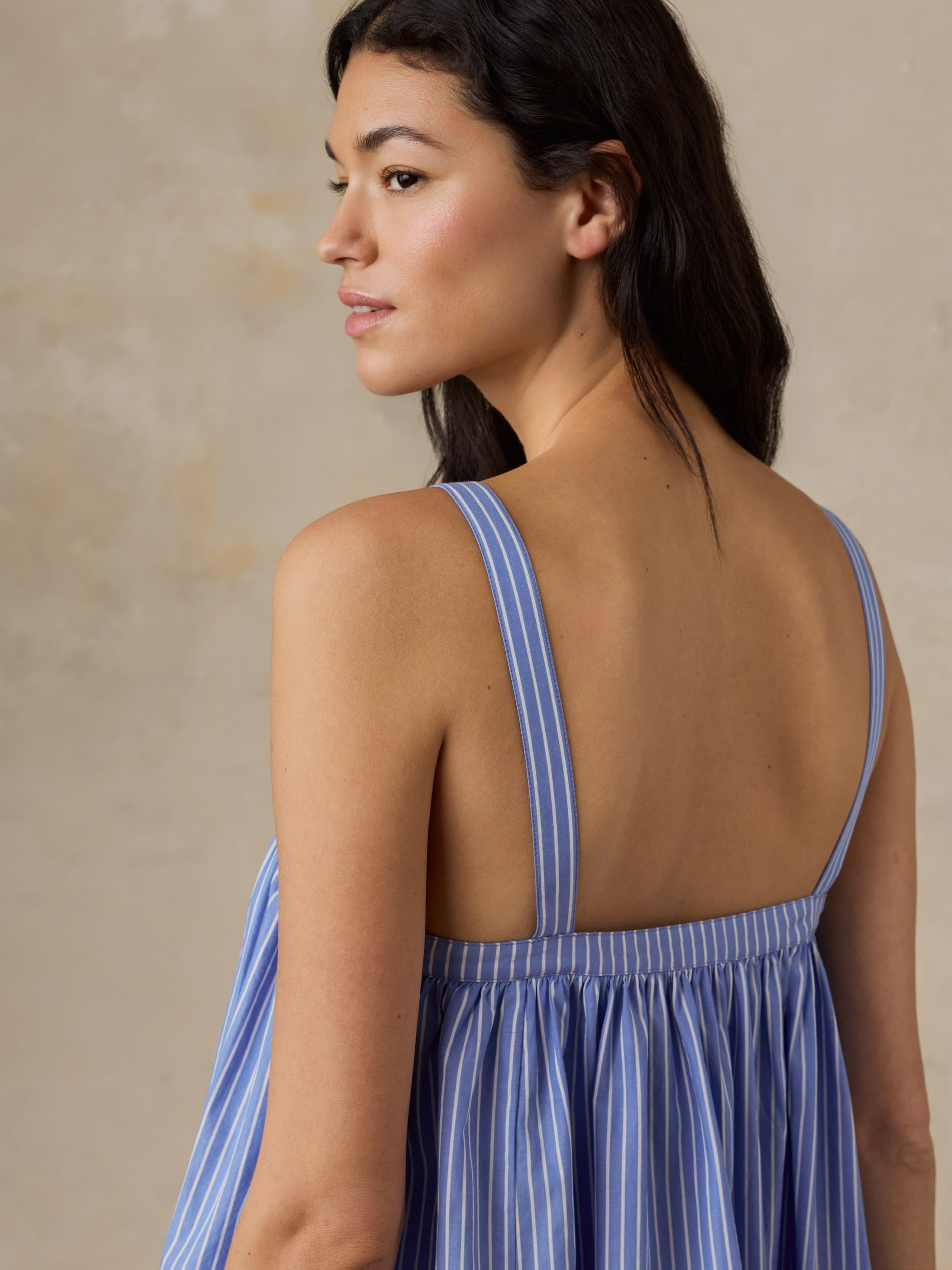 Woman wearing a blue striped dress with a beige background