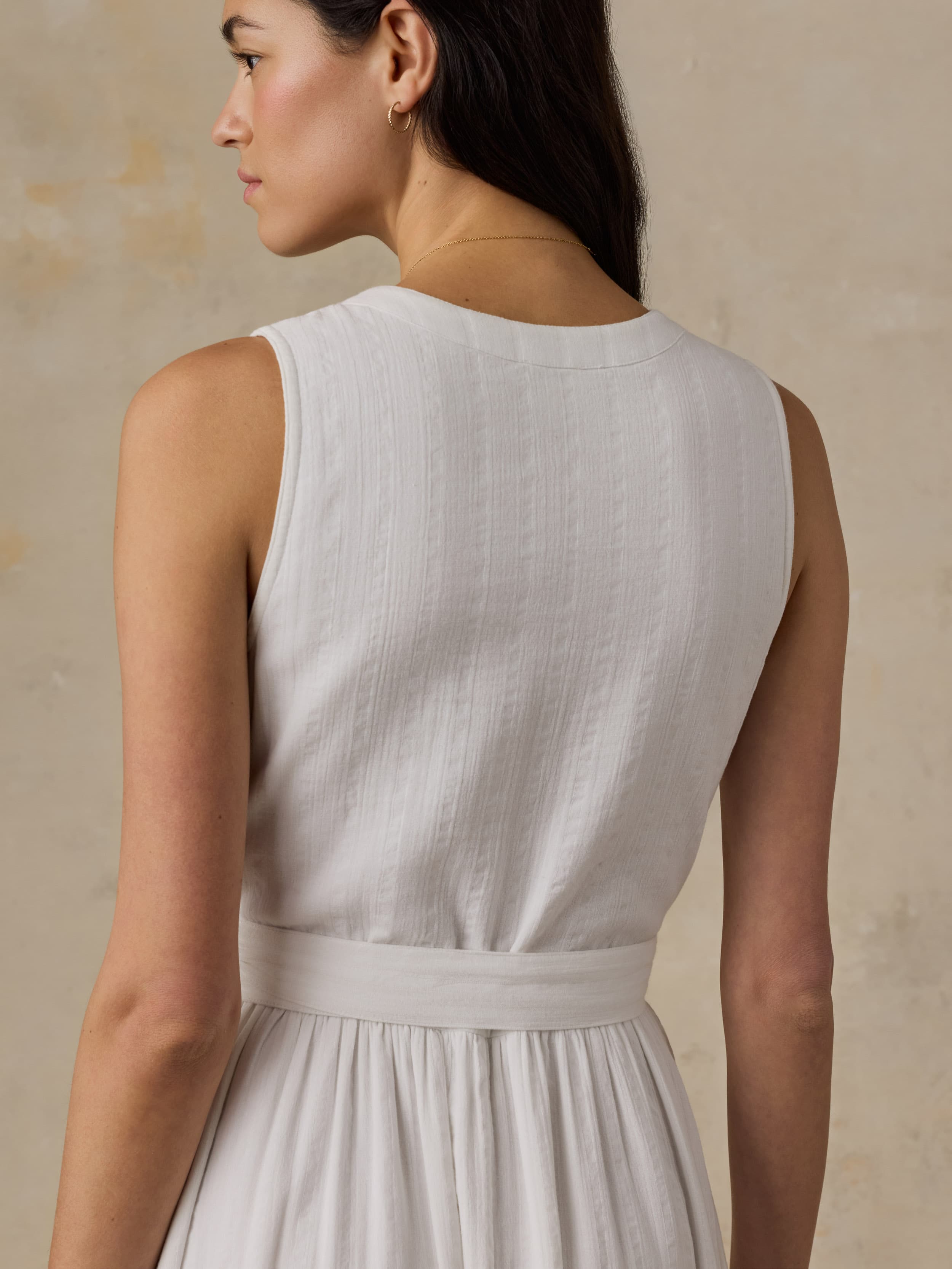 Woman wearing a white dress against a beige background