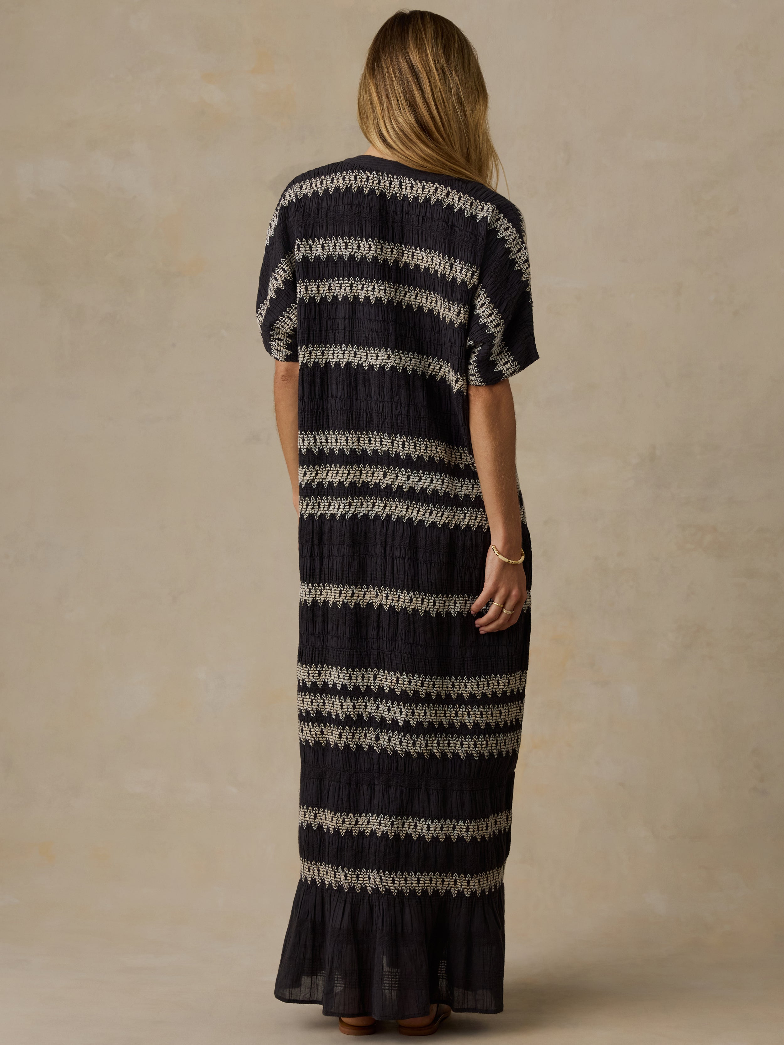 Woman wearing a black and white striped dress against a beige background