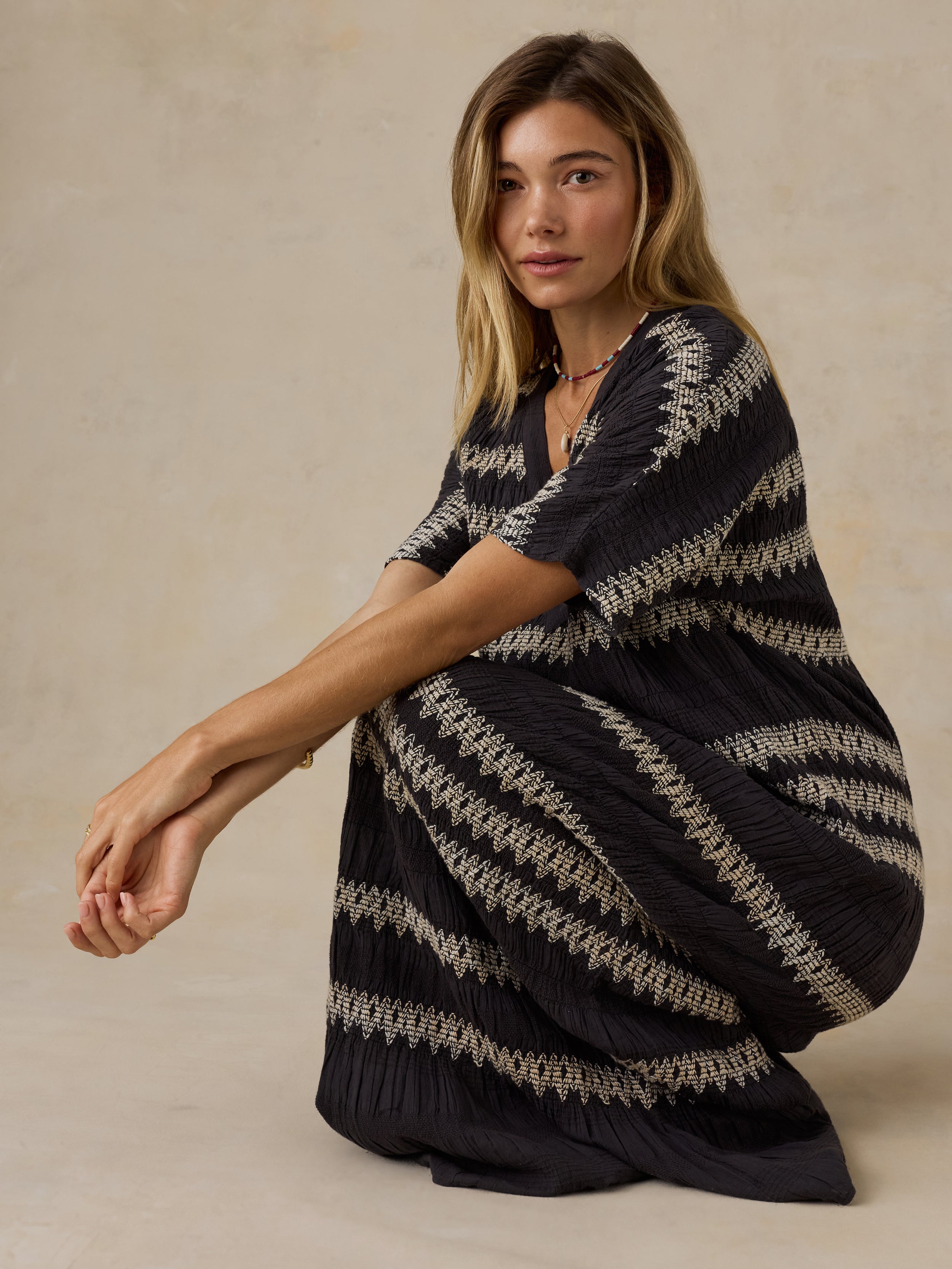 Woman wearing a black and white striped dress against a beige background