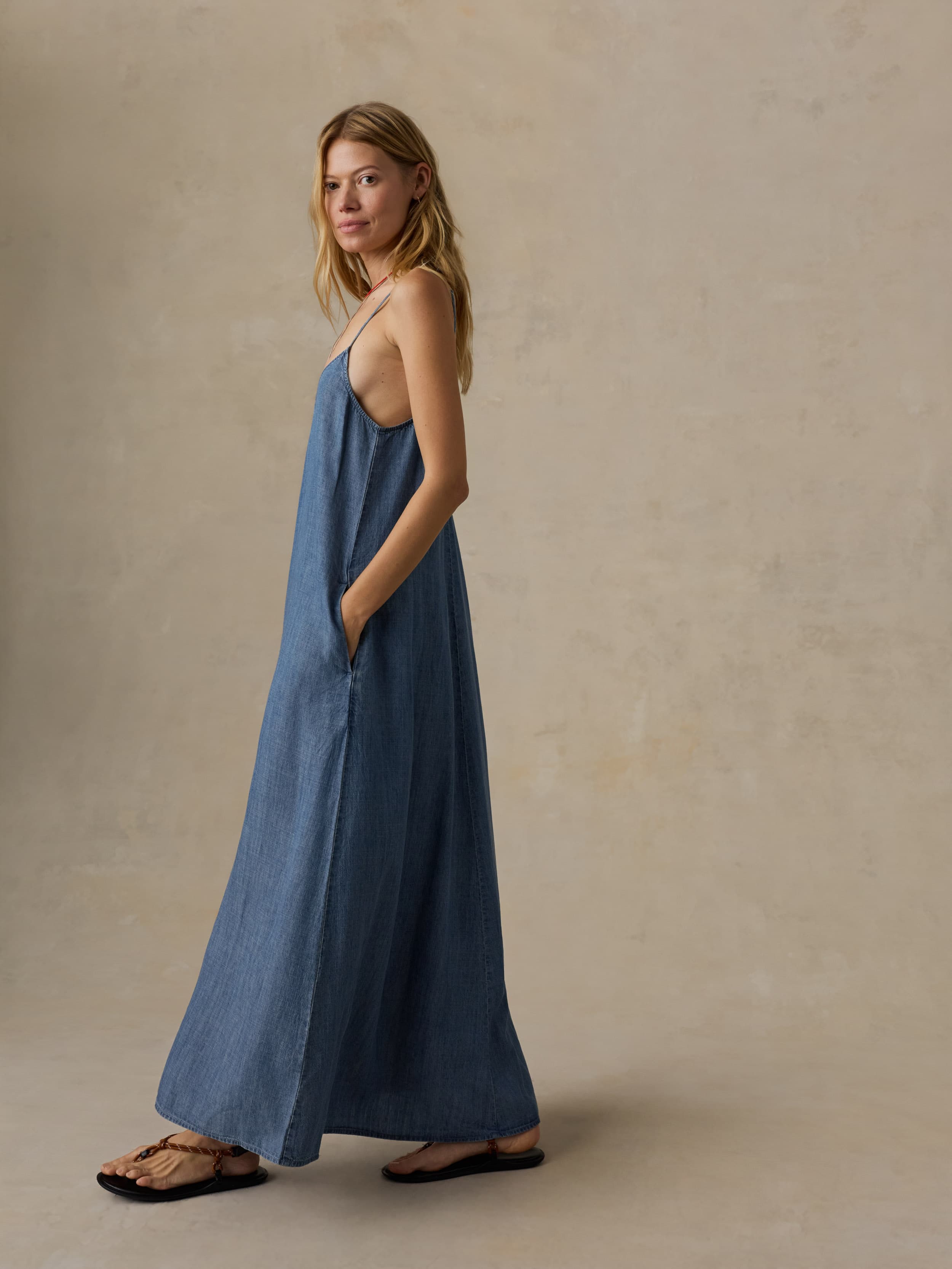 Woman wearing a blue maxi dress against a beige background