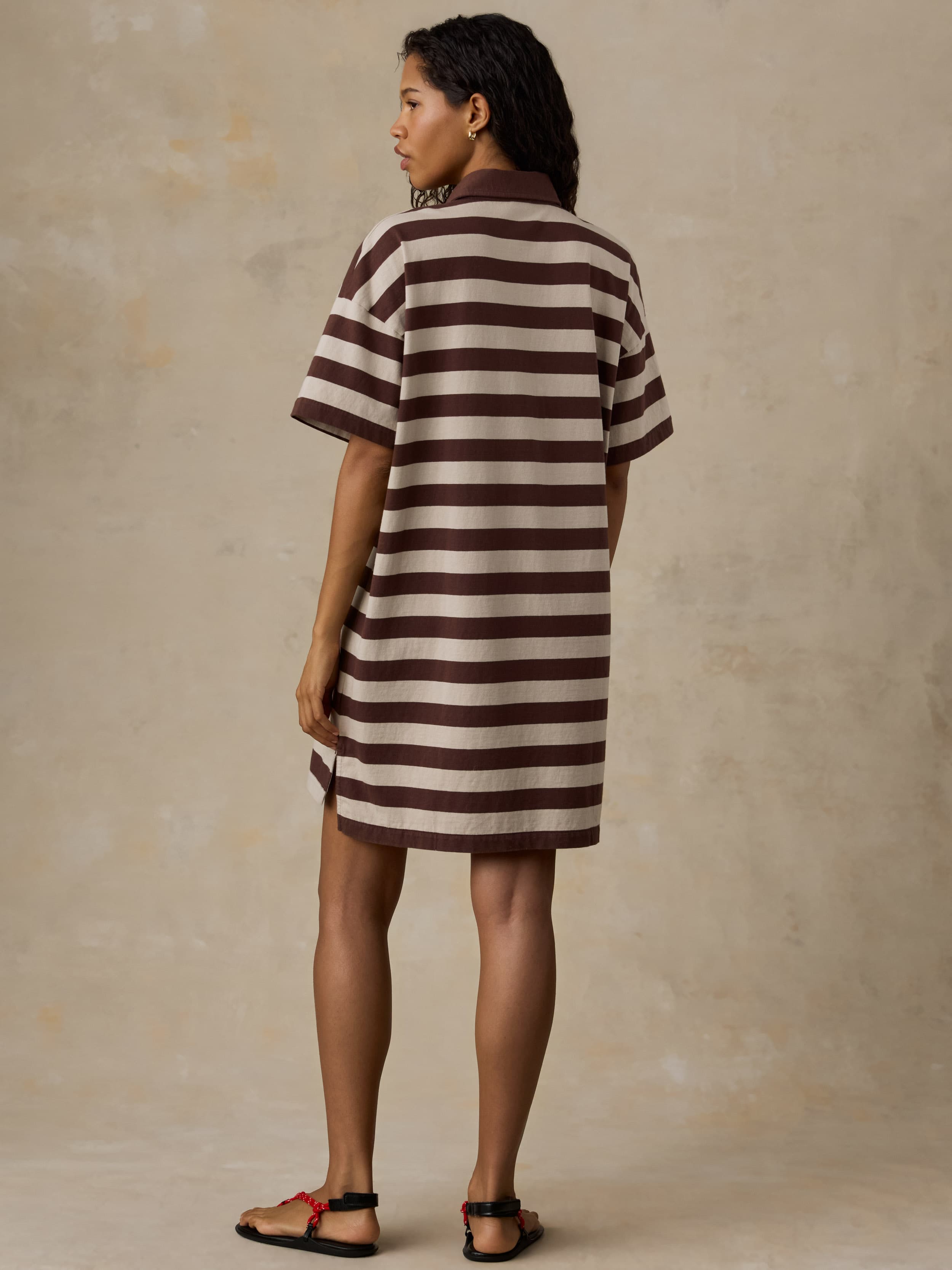 Woman wearing a brown and white striped dress against a beige background
