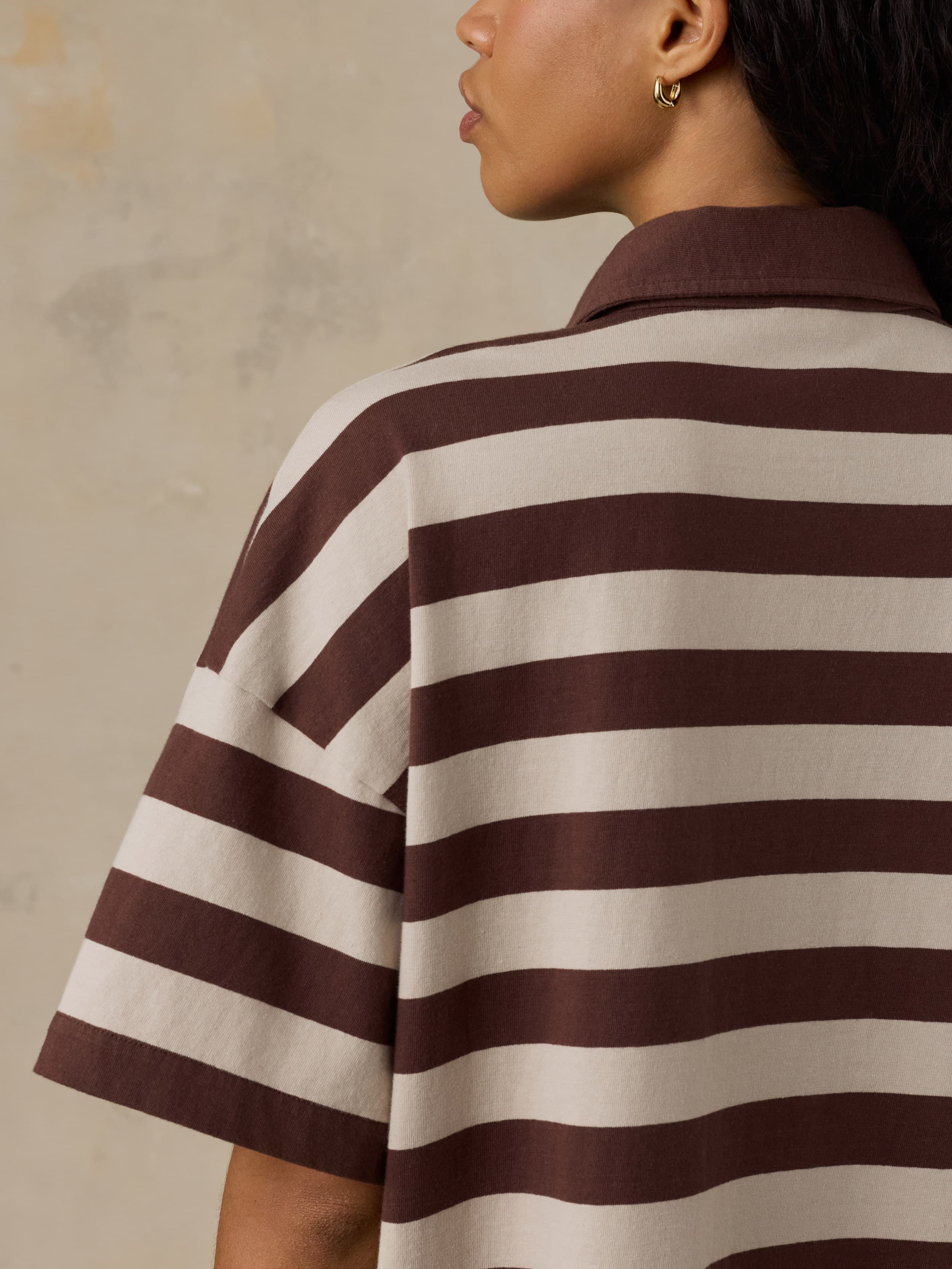 Woman wearing a brown and beige striped dress against a neutral background