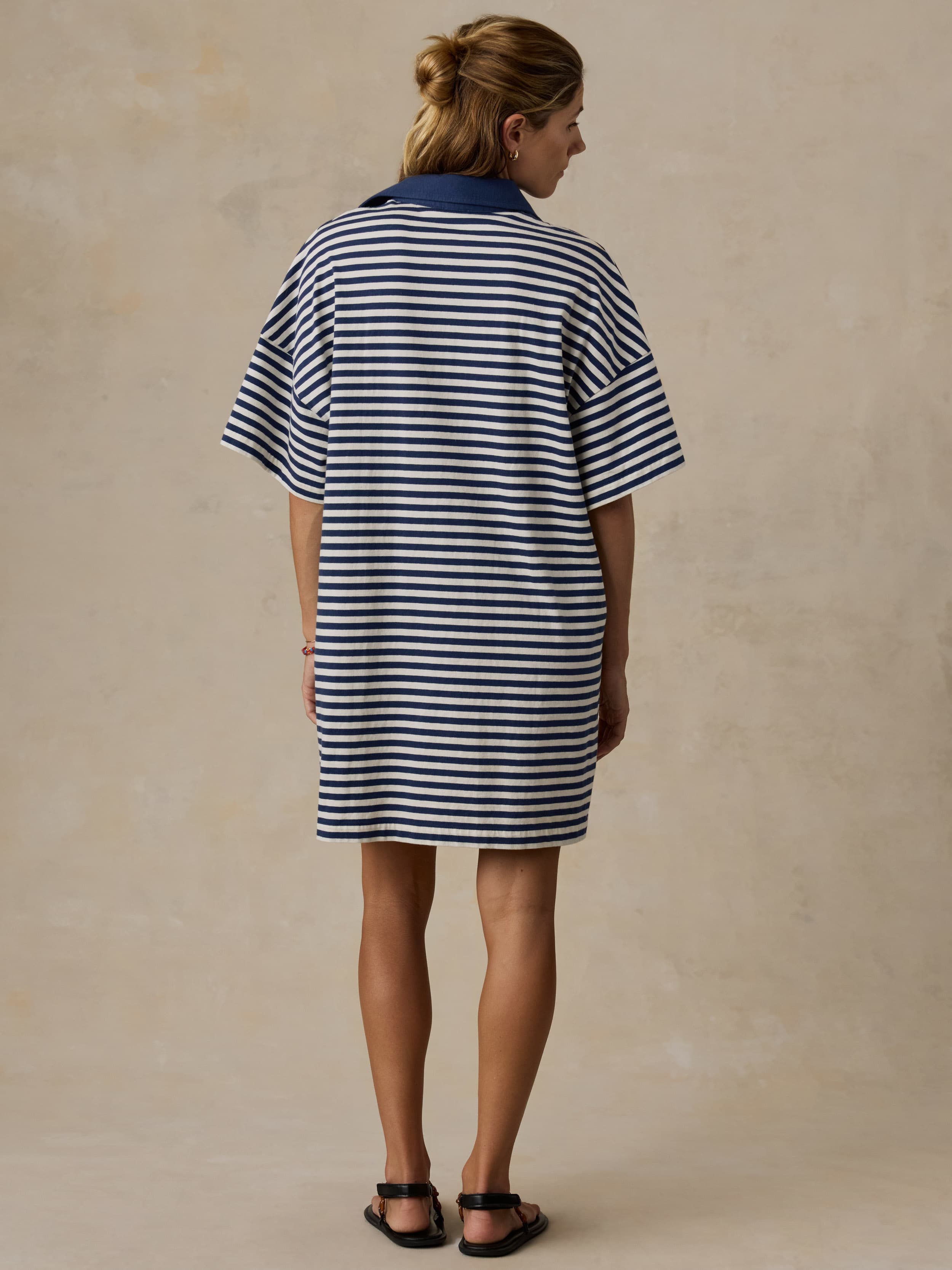 Woman wearing a blue and white striped dress against a beige background