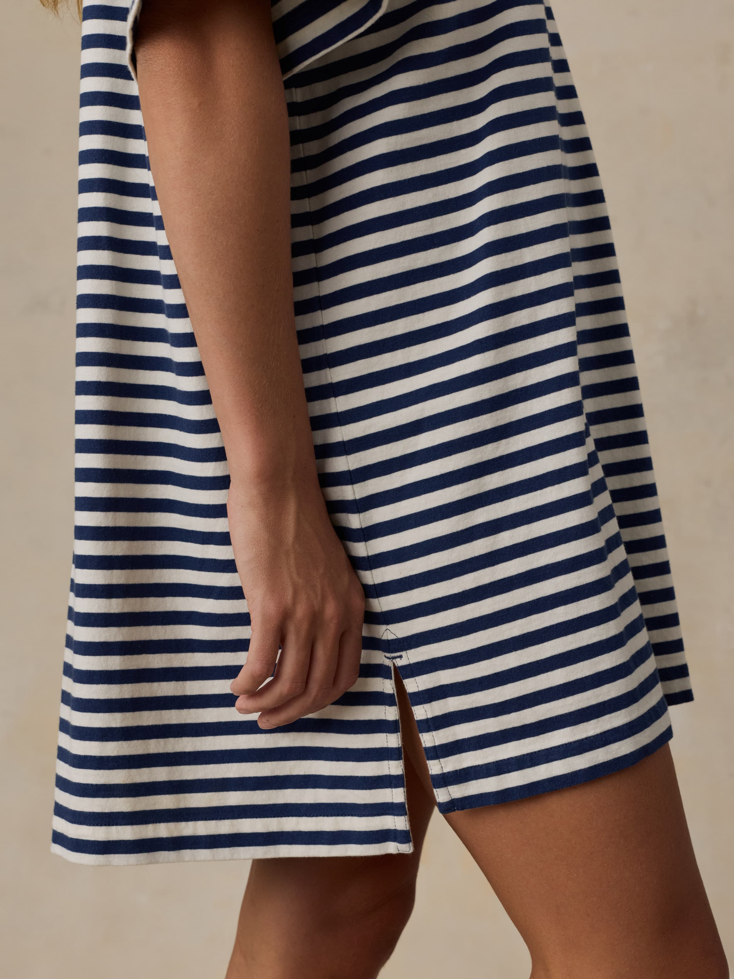 Woman wearing a blue and white striped dress against a beige background