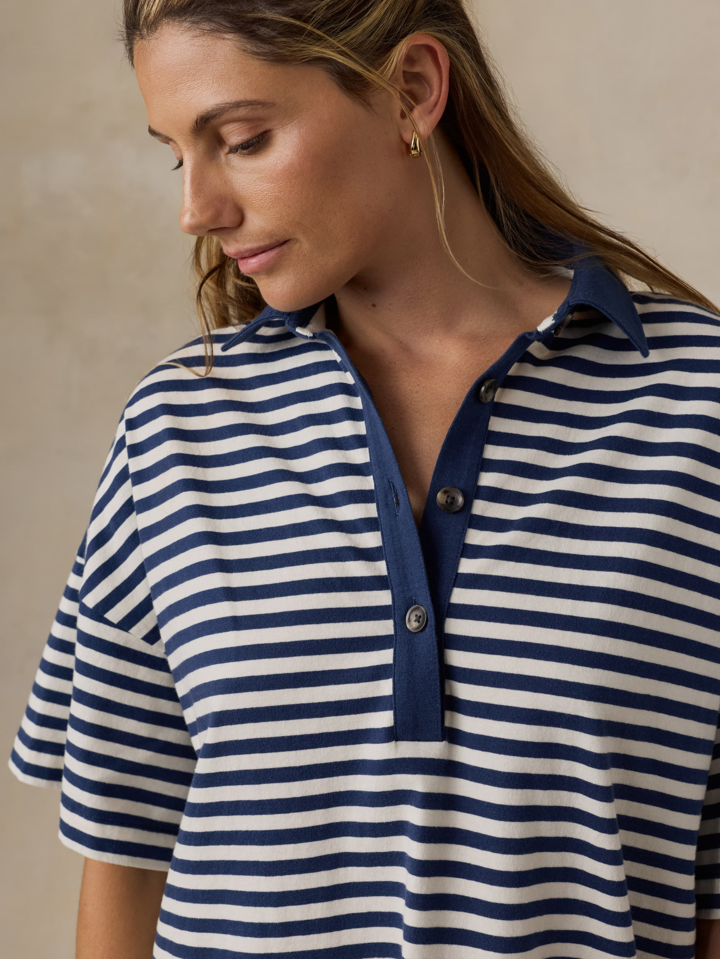 Woman wearing a blue and white striped dress against a beige background