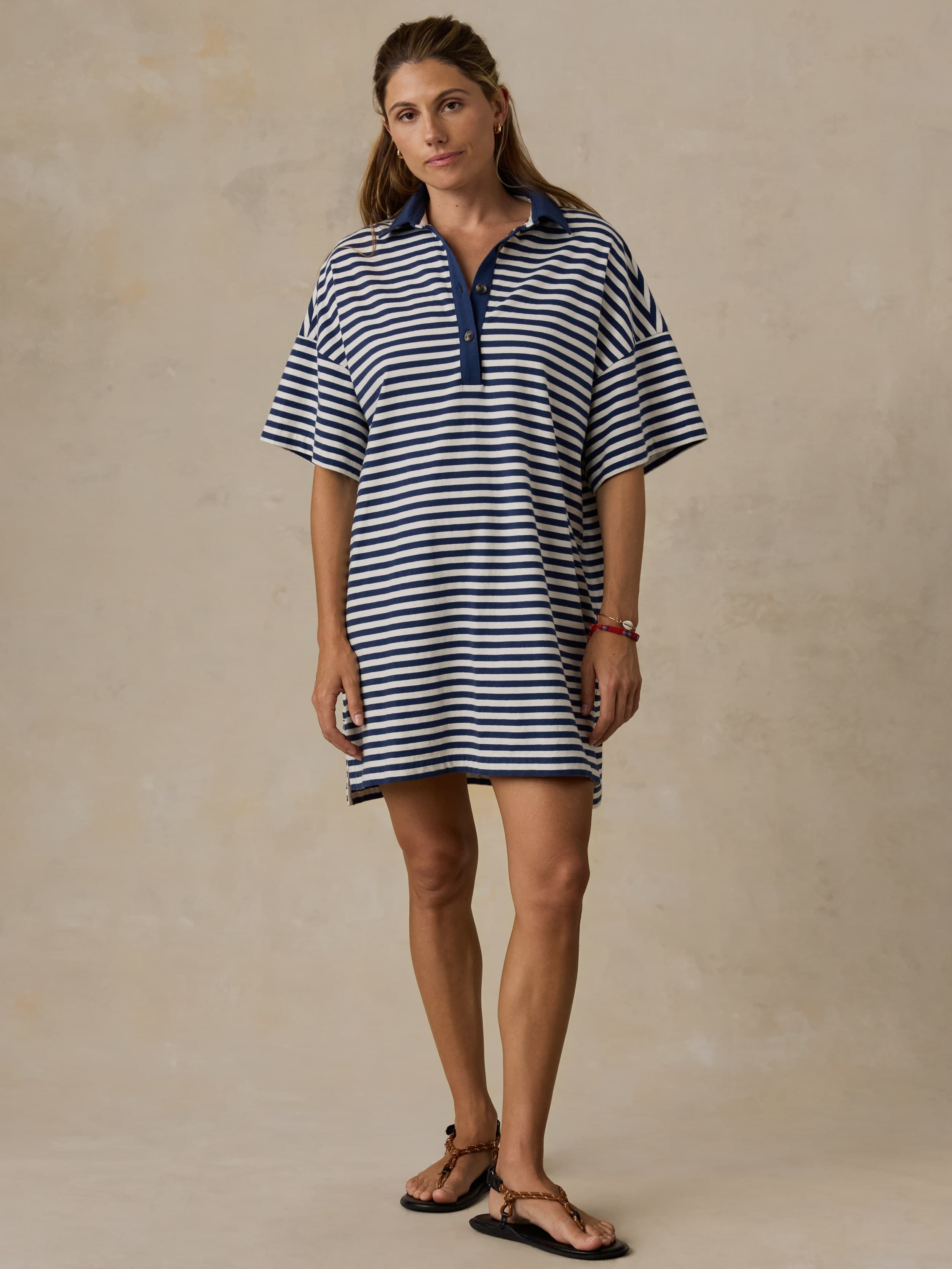 Woman wearing a blue and white striped dress against a beige background