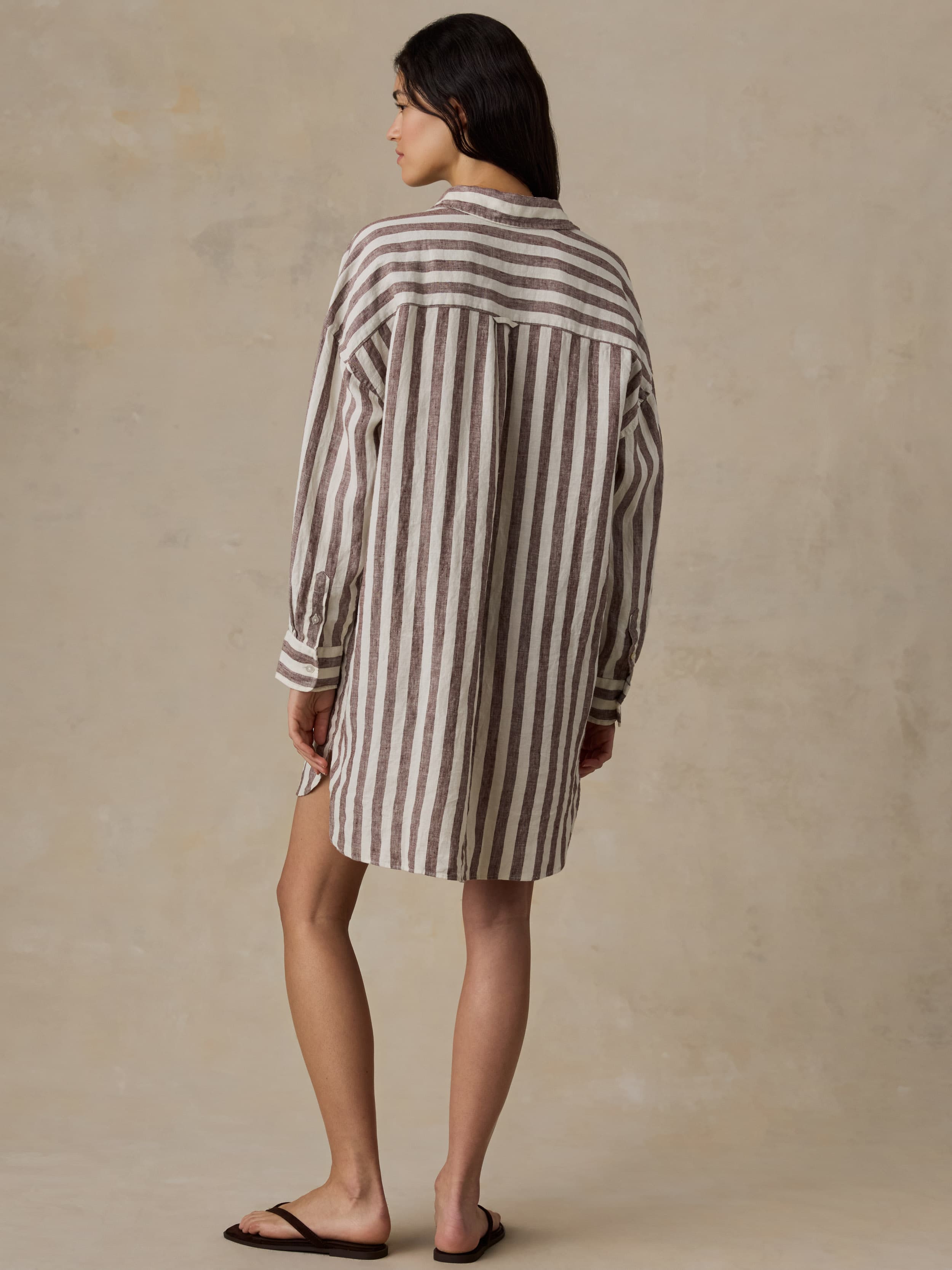 Woman wearing a striped shirt dress against a beige background