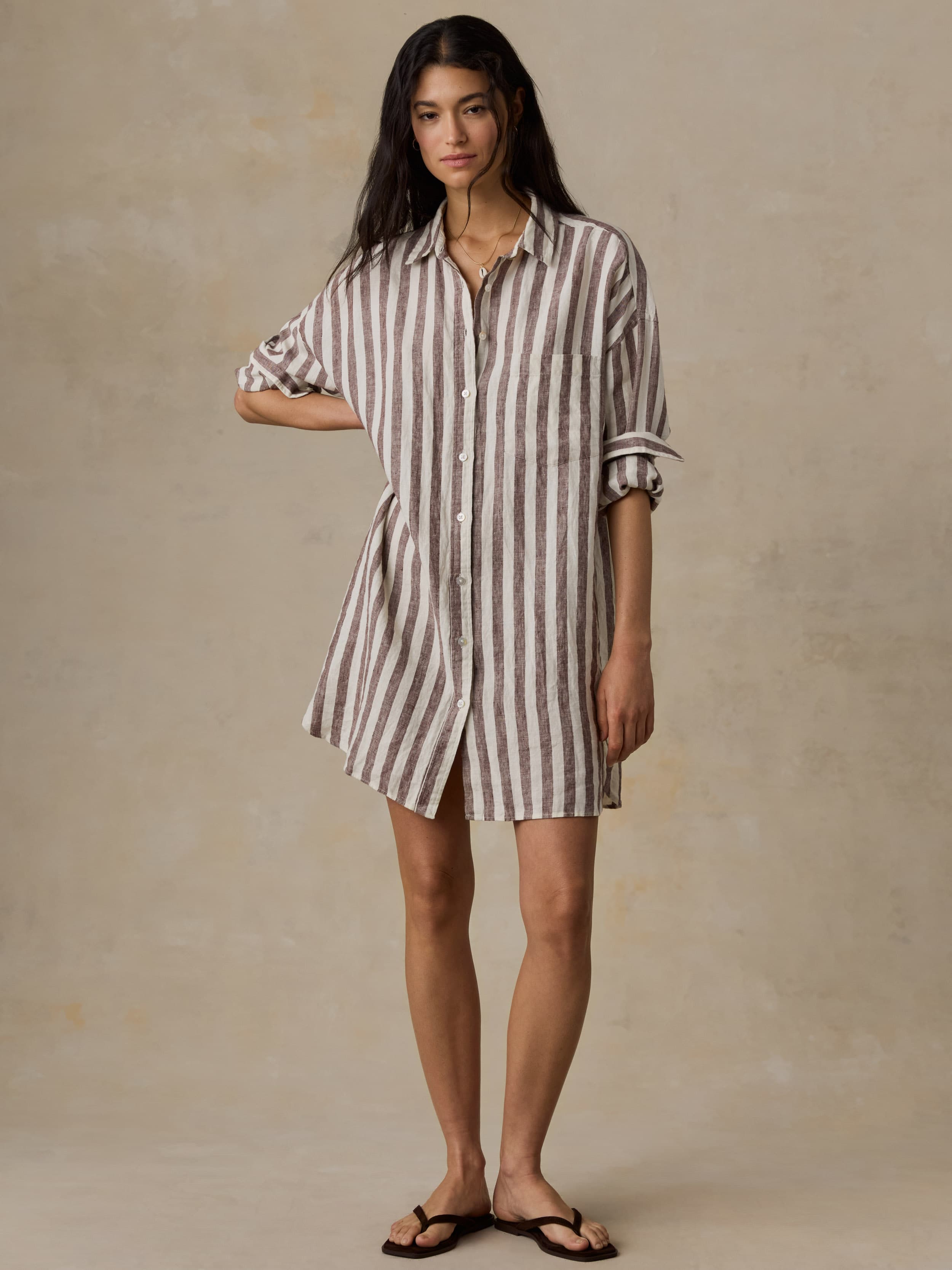Woman wearing a striped shirt dress against a plain background