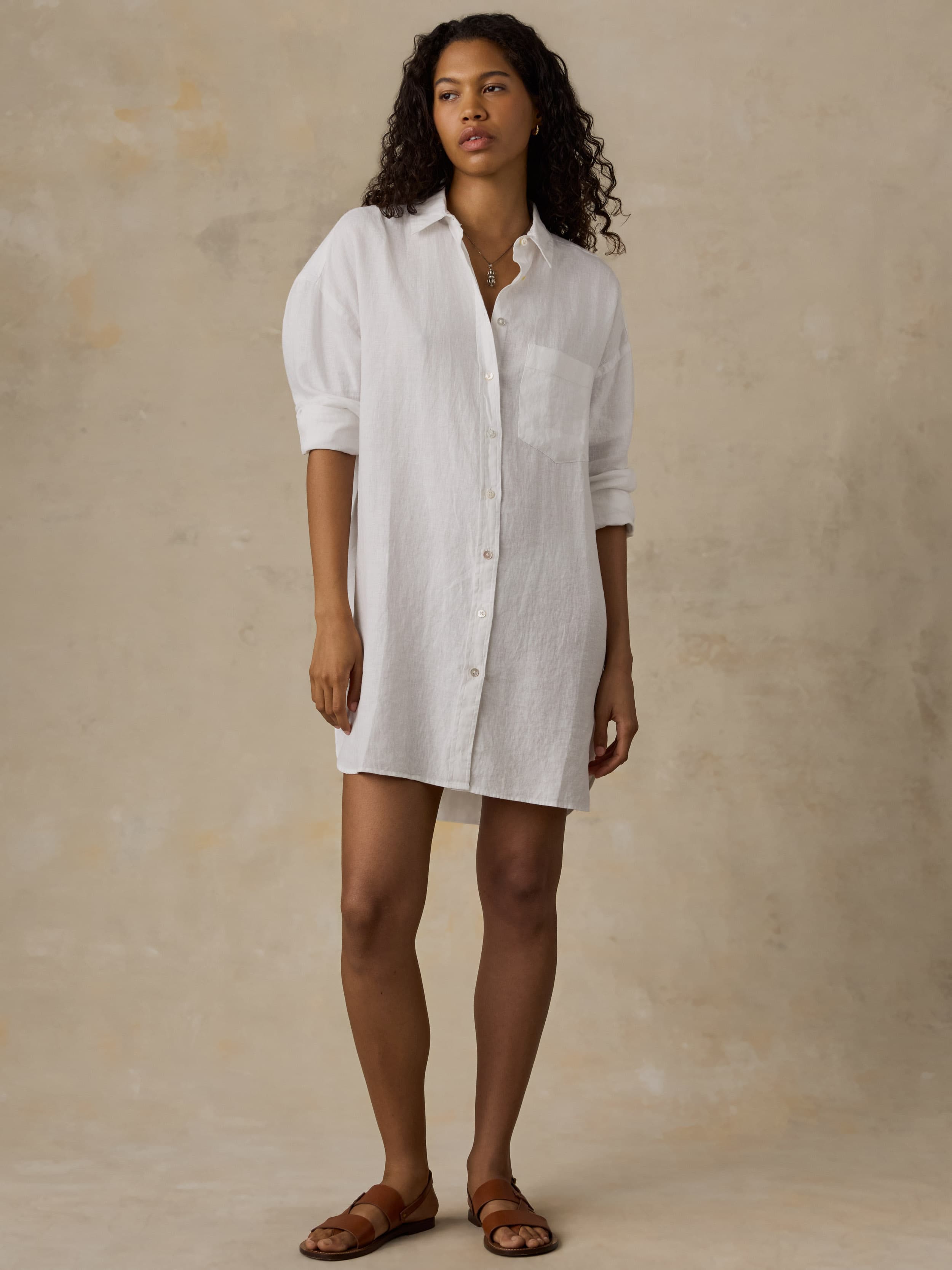 Woman wearing a white shirtdress against a beige background