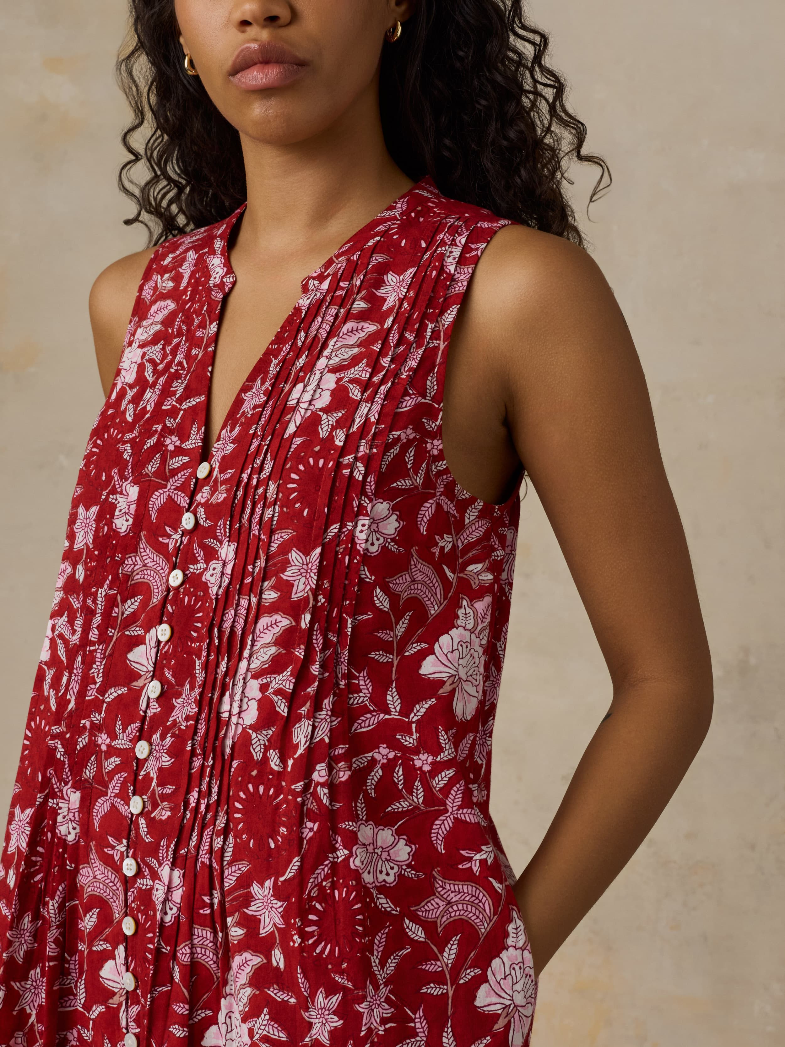 Woman wearing a red floral dress against a neutral background