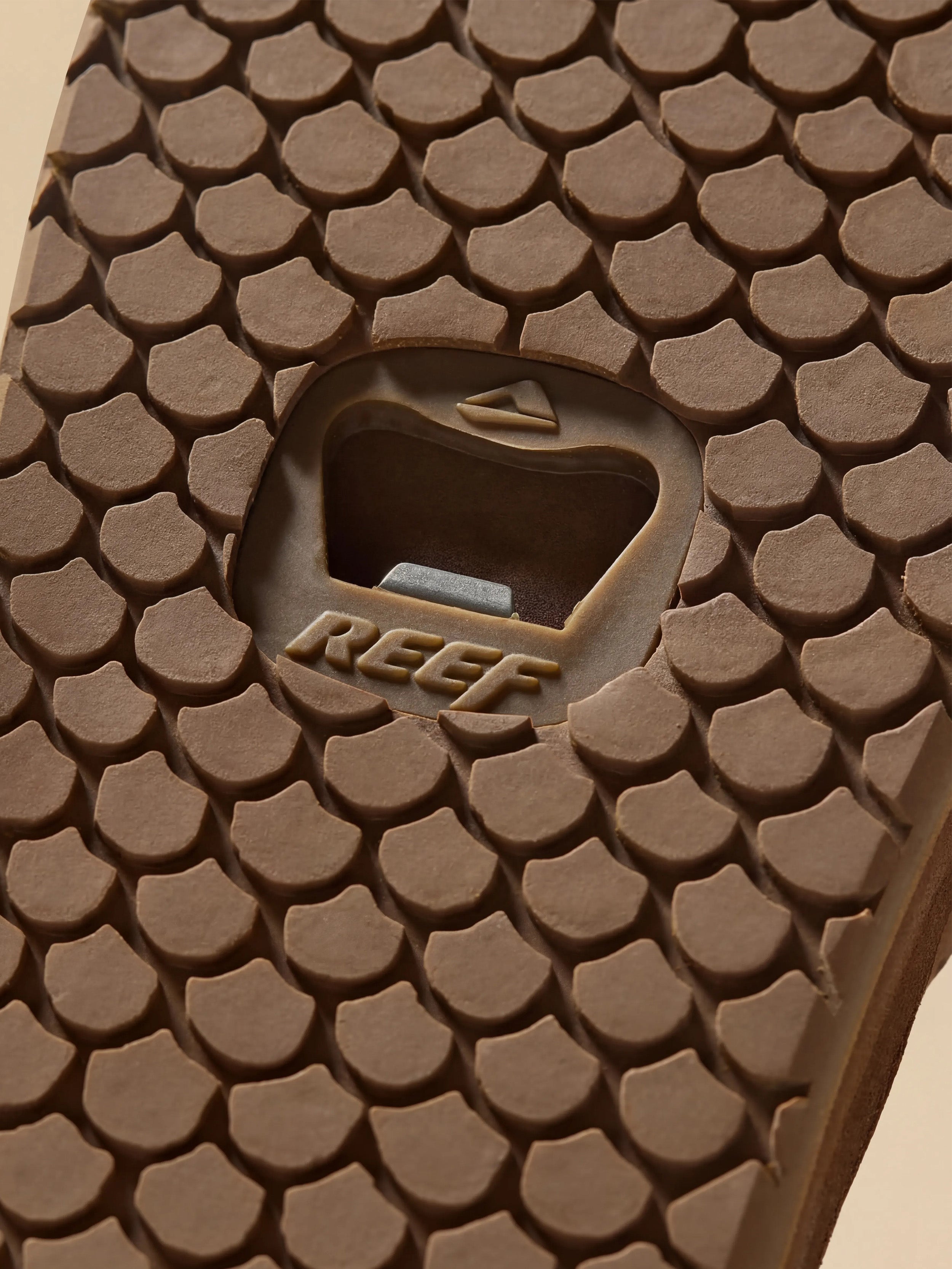 Close-up of a brown sandal sole with bottle opener detail and 'REEF' branding.
